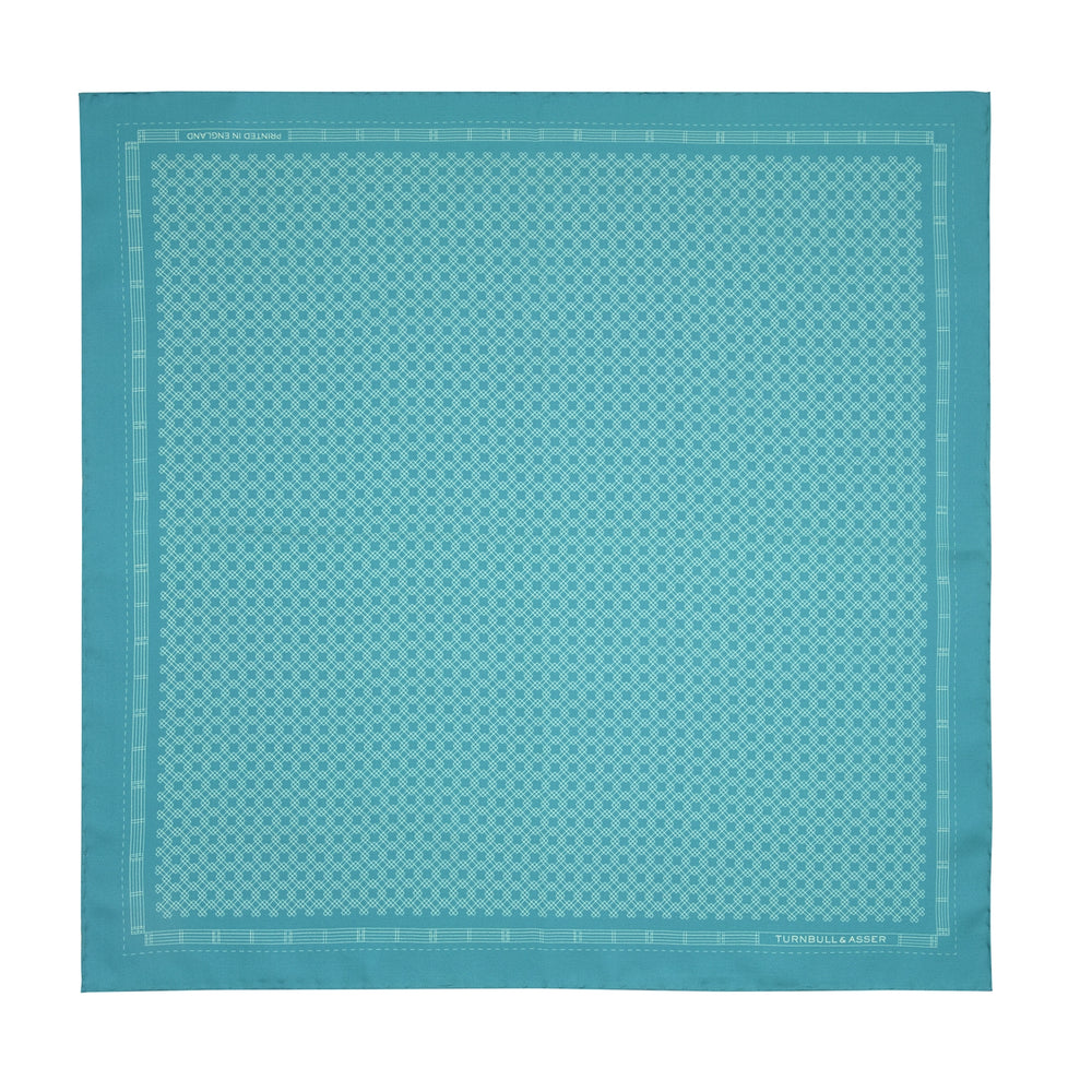 The Kingfisher Green Monocle Silk Pocket Square by Turnbull & Asser features an elegant geometric pattern and border, with the Turnbull & Asser name displayed in white on the lower right corner.