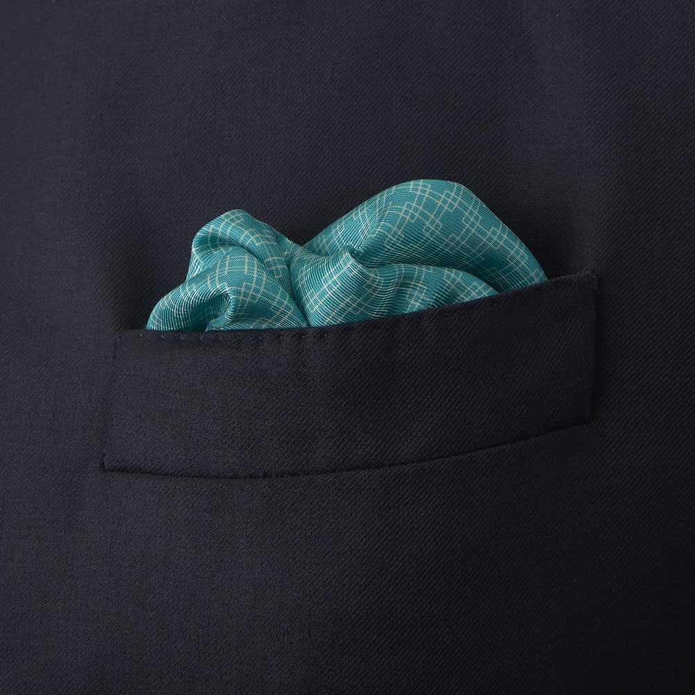 The Kingfisher Green Monocle Silk Pocket Square by Turnbull & Asser features an elegant geometric pattern and border, with the Turnbull & Asser name displayed in white on the lower right corner.