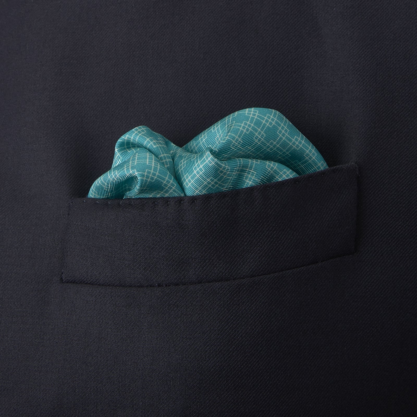 View 4 of product The Kingfisher Green Monocle Silk Pocket Square by Turnbull & Asser features an elegant geometric pattern and border, with the Turnbull & Asser name displayed in white on the lower right corner.