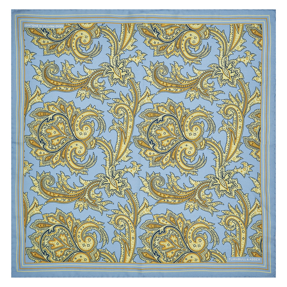 A folded Light Blue and Yellow Large Paisley Silk Pocket Square by Turnbull & Asser features an intricate paisley design. The brand name appears in white on the bottom right corner.