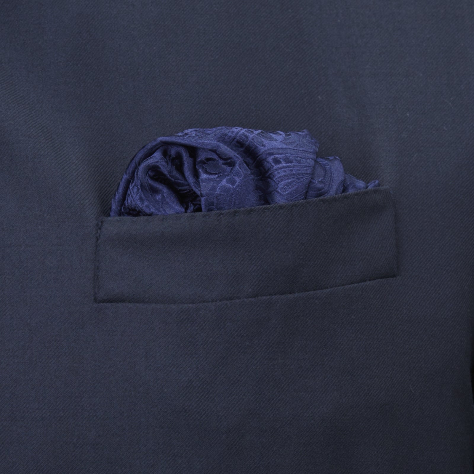 View 4 of product The Navy House Paisley Hand-Rolled Silk Pocket Square by Turnbull & Asser, shown folded to display its pattern against a white background, adds an elegant touch to black tie attire.