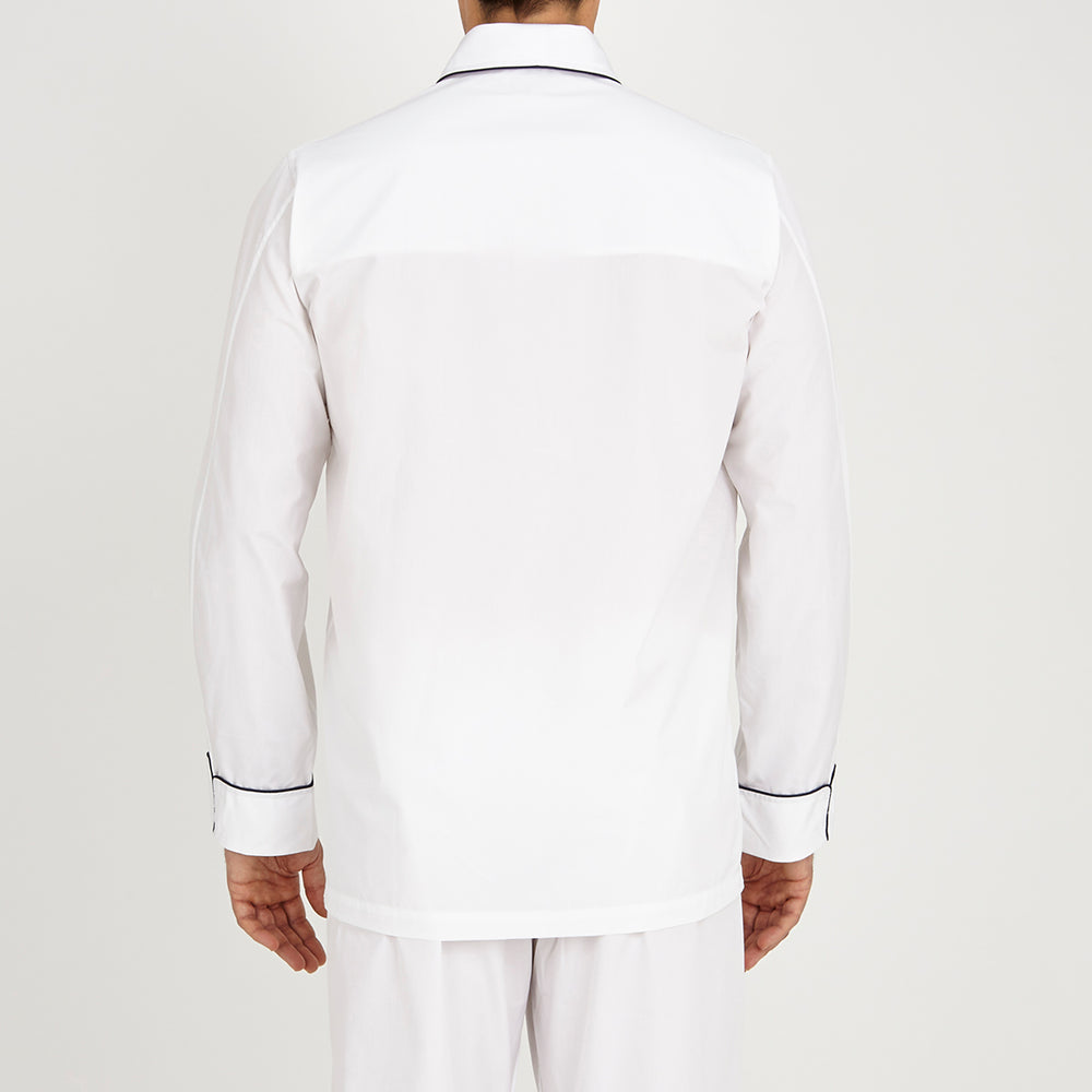 The Turnbull & Asser White Piped Cotton Pyjama Set, made from Egyptian cotton and featuring black piping and two buttons, is shown folded with a matching white tie-strap face mask on a light gray background.