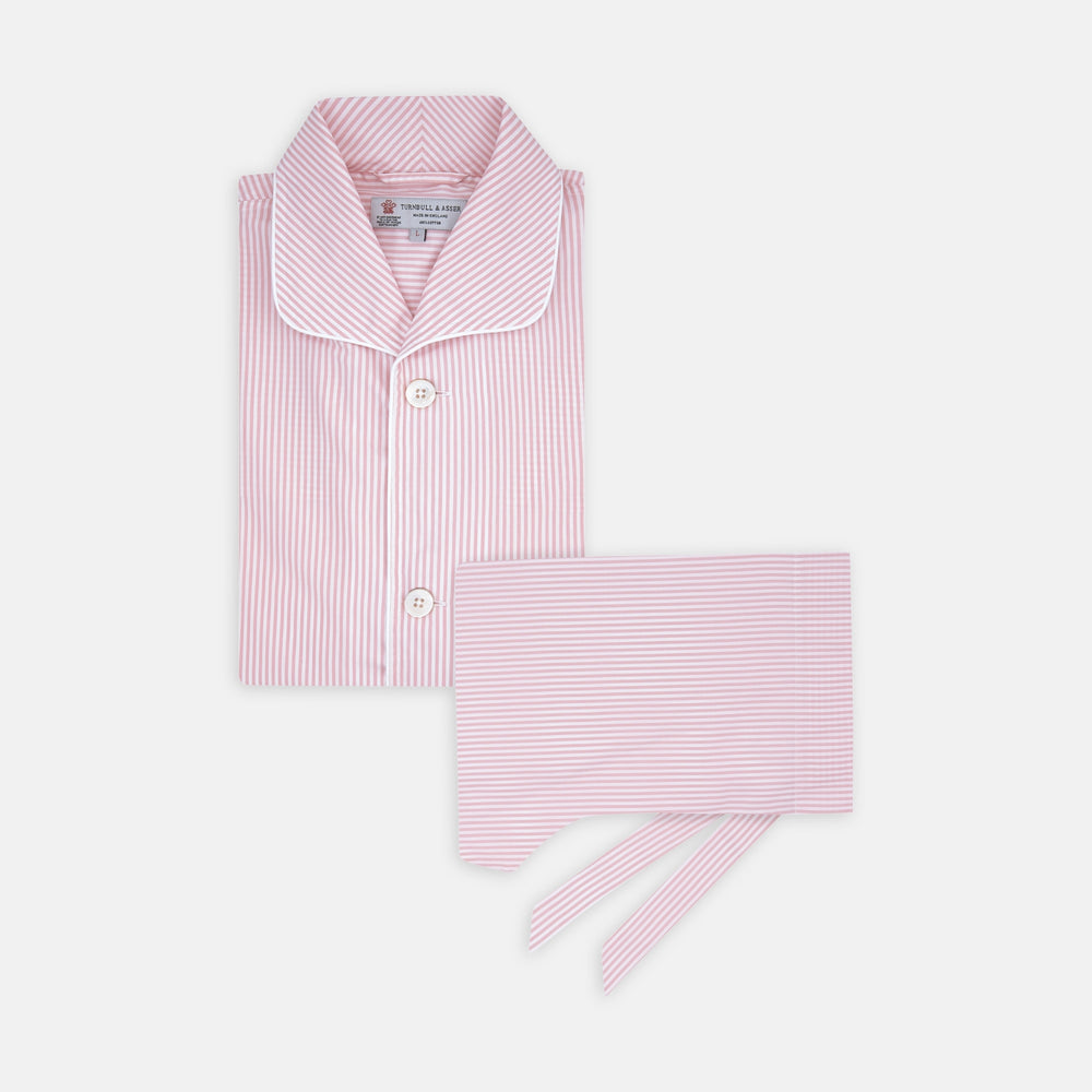 The Turnbull & Asser Pink Bengal Stripe Piped Cotton Pyjama Set features a folded pink and white striped top with white buttons and a matching fabric belt, both displayed flat on a light background.