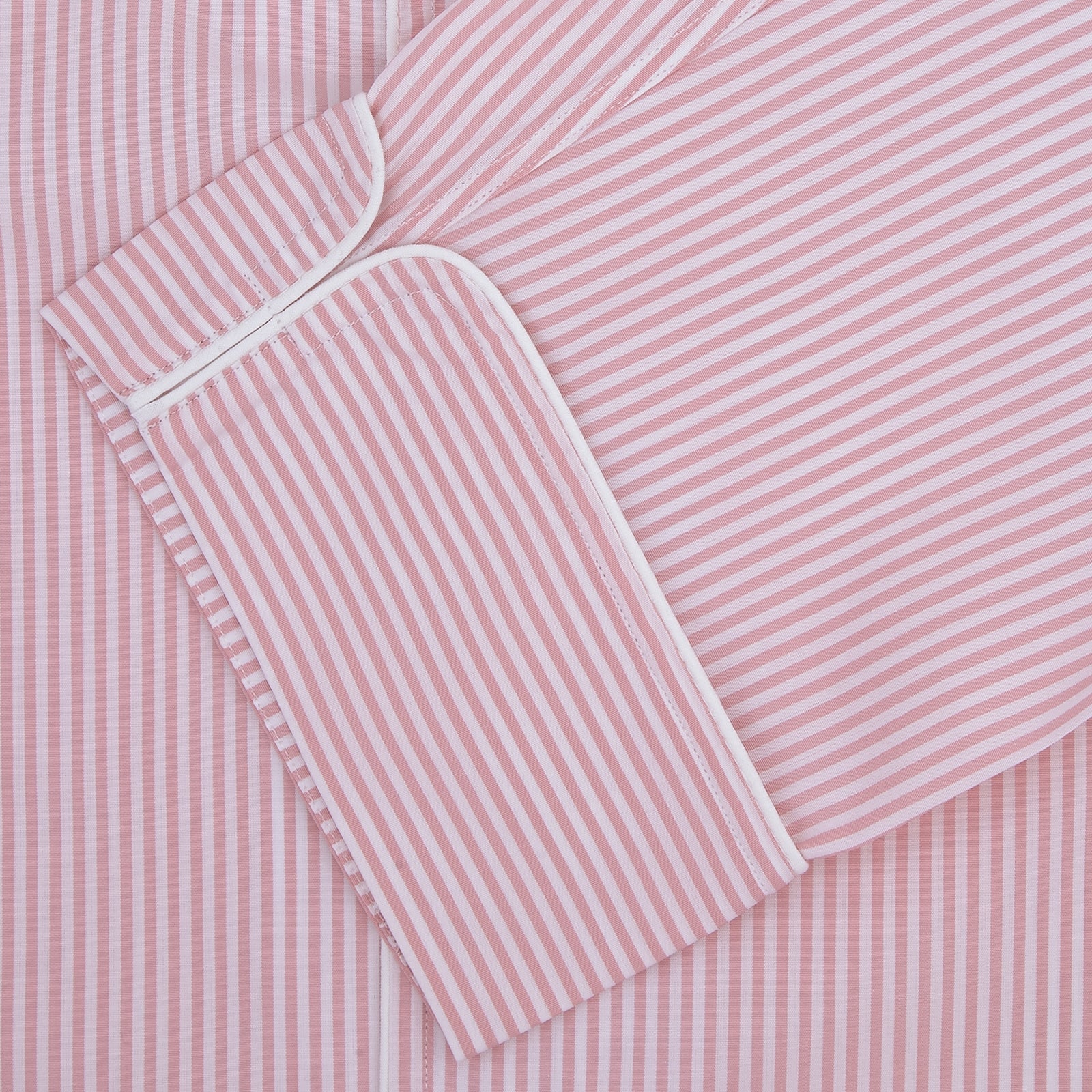 View 2 of product The Turnbull & Asser Pink Bengal Stripe Piped Cotton Pyjama Set features a folded pink and white striped top with white buttons and a matching fabric belt, both displayed flat on a light background.