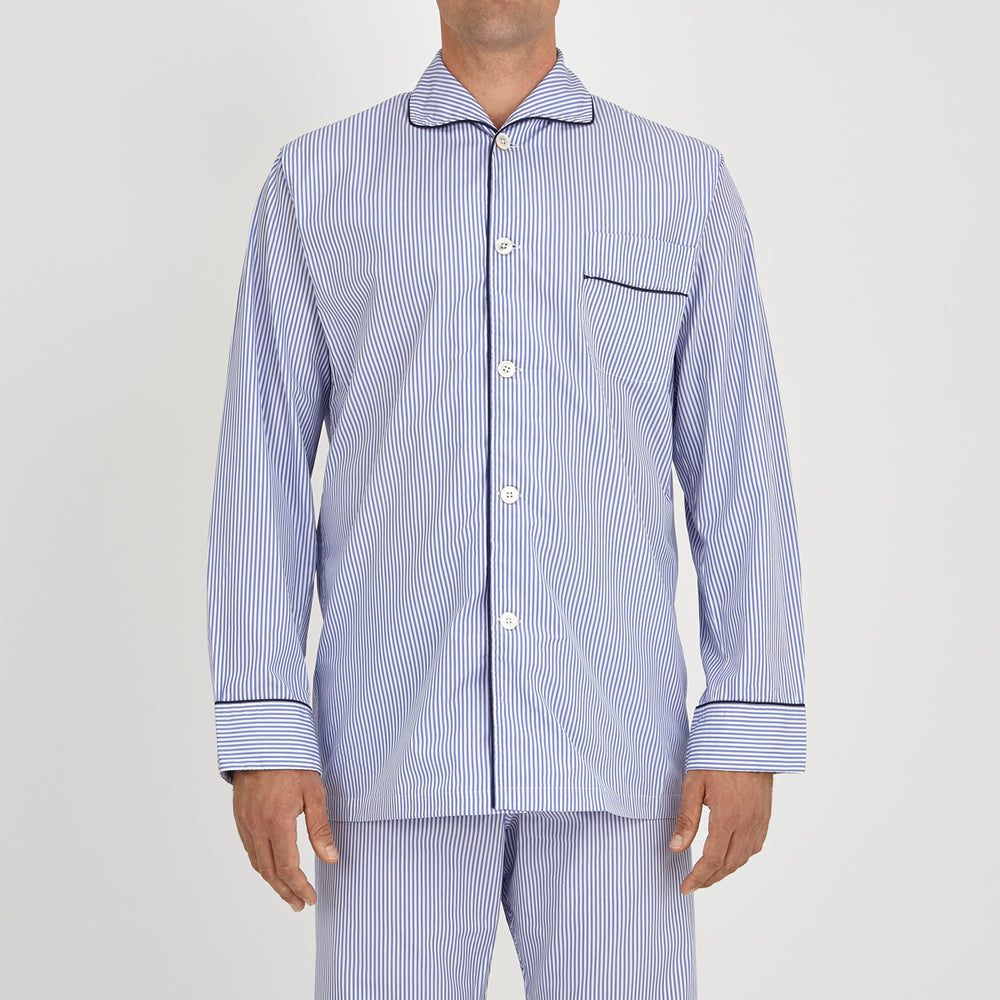 The Turnbull & Asser Blue Bengal Stripe Piped Cotton Pyjama Set, featuring a folded top with white buttons beside matching bottoms, is displayed on a plain light background.