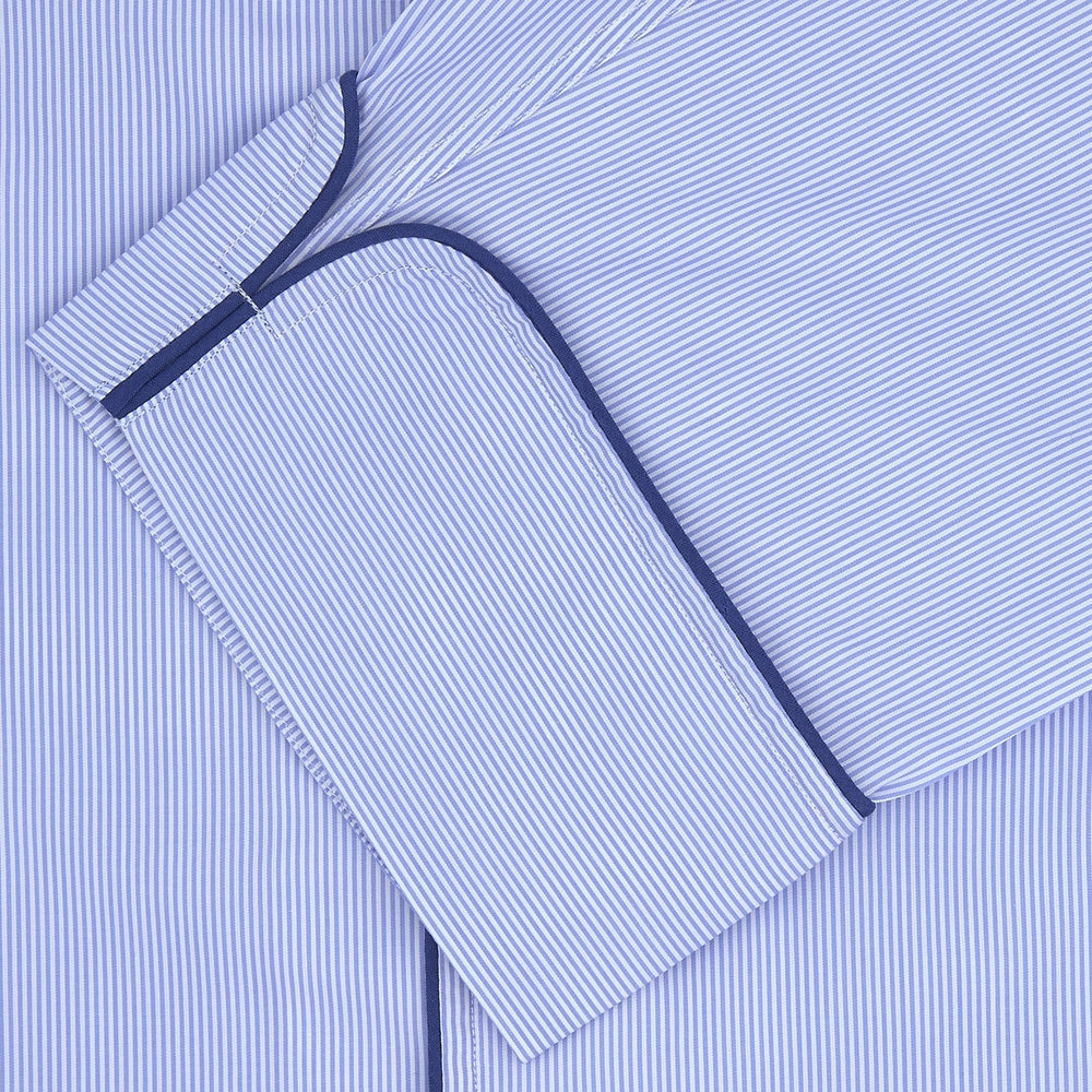 The Turnbull & Asser Blue Fine Stripe Piped Sea Island Quality Cotton Pyjama Set, featuring a button-up shirt and matching nightcap, is neatly folded and displayed on a plain white background.