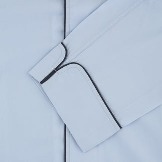 The Light Blue Piped Sea Island Quality Cotton Pyjama Set by Turnbull & Asser, shown with a matching face mask, features dark piping and is crafted from premium cotton, all displayed on a plain white background for a luxurious look.