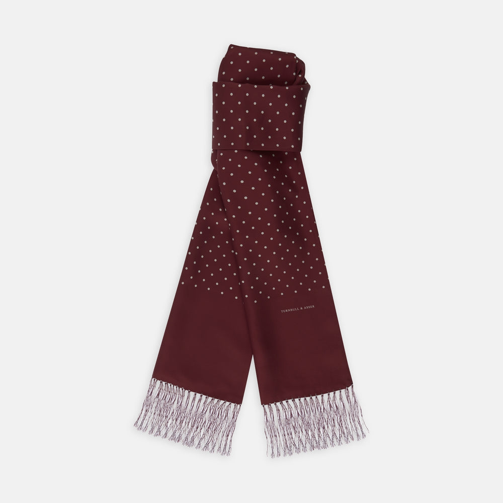 The Turnbull & Asser Wine Spotted Silk Scarf features white polka dots and white fringed ends, elegantly tasseled and neatly folded against a plain white background.