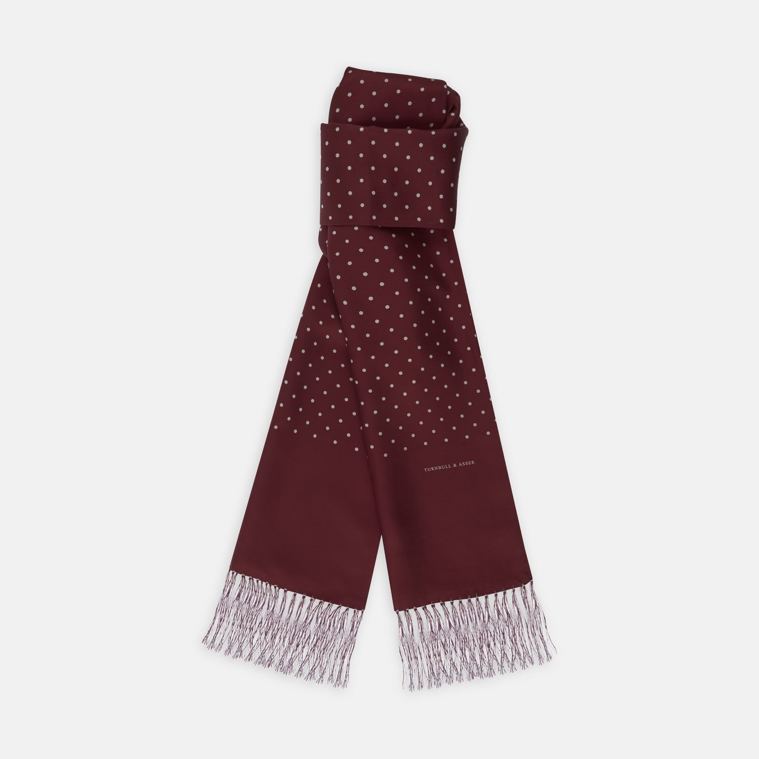 View 1 of product The Turnbull & Asser Wine Spotted Silk Scarf features white polka dots and white fringed ends, elegantly tasseled and neatly folded against a plain white background.
