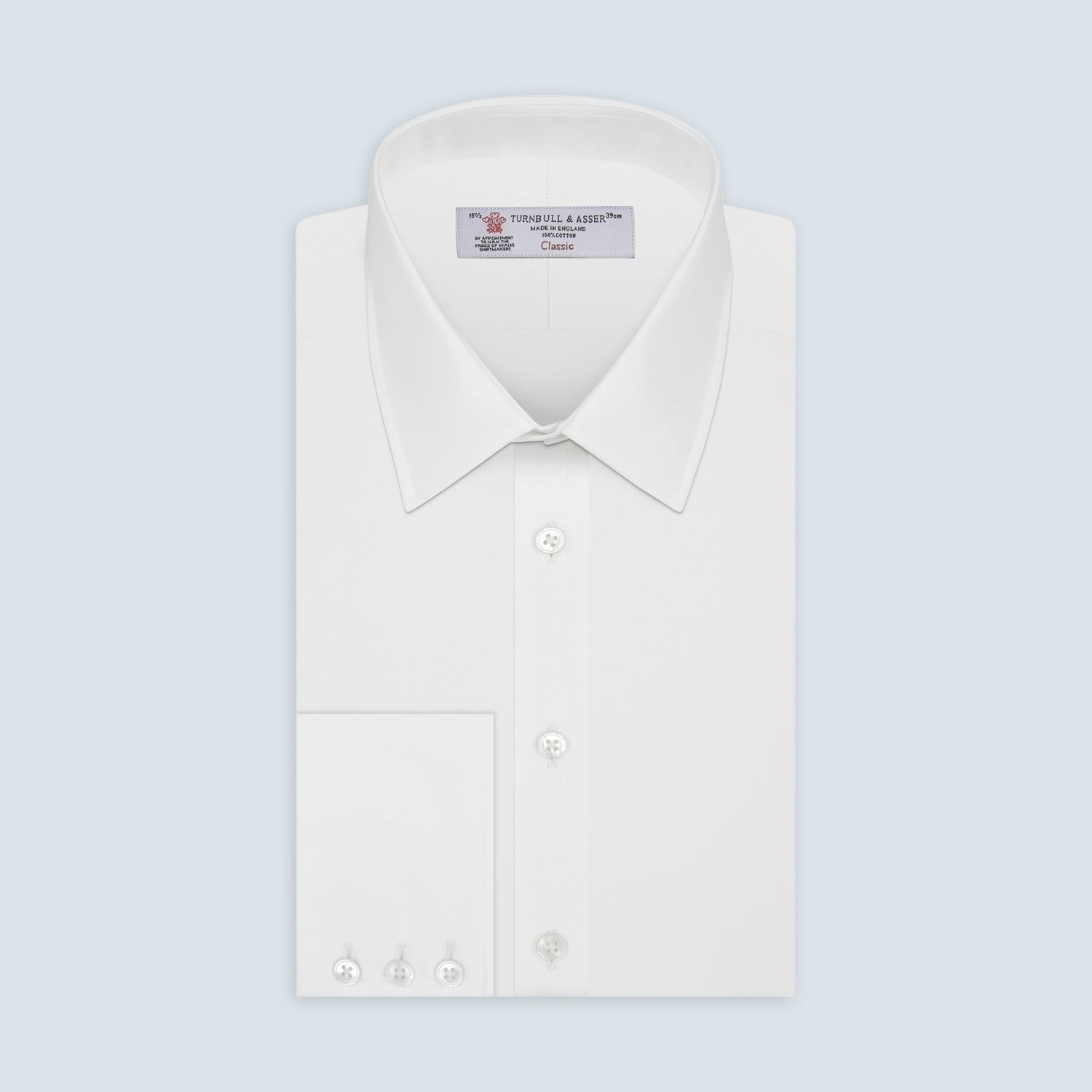 View 2 of product A circular swatch of Turnbull & Asser’s Plain White Cotton Fabric is shown against a light gray background, highlighting its smooth texture and a subtle stitched edge on the right side.