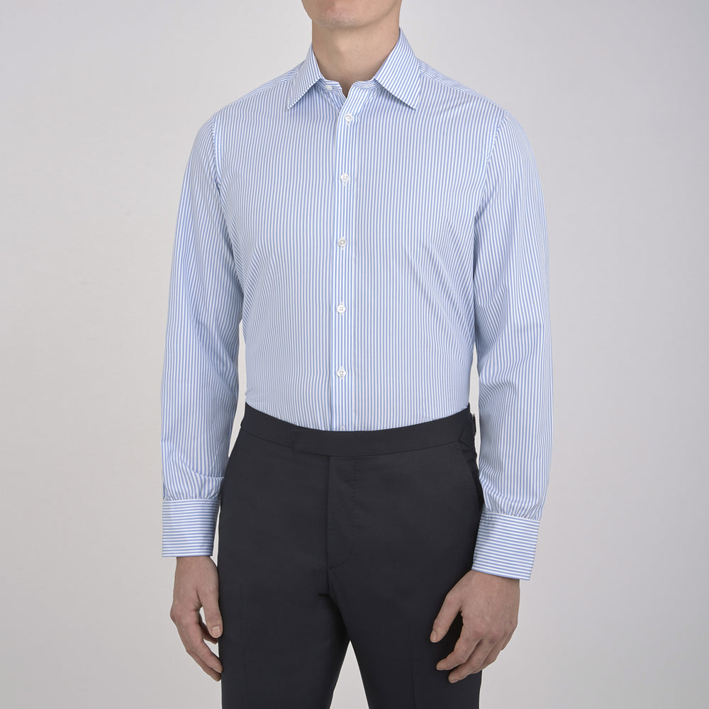 The Turnbull & Asser Light Blue Bengal Stripe Shirt features white vertical stripes, a classic T&A collar, and 3-button cuffs. Buttoned down the front, it’s laid flat on a white background for a timeless British look.