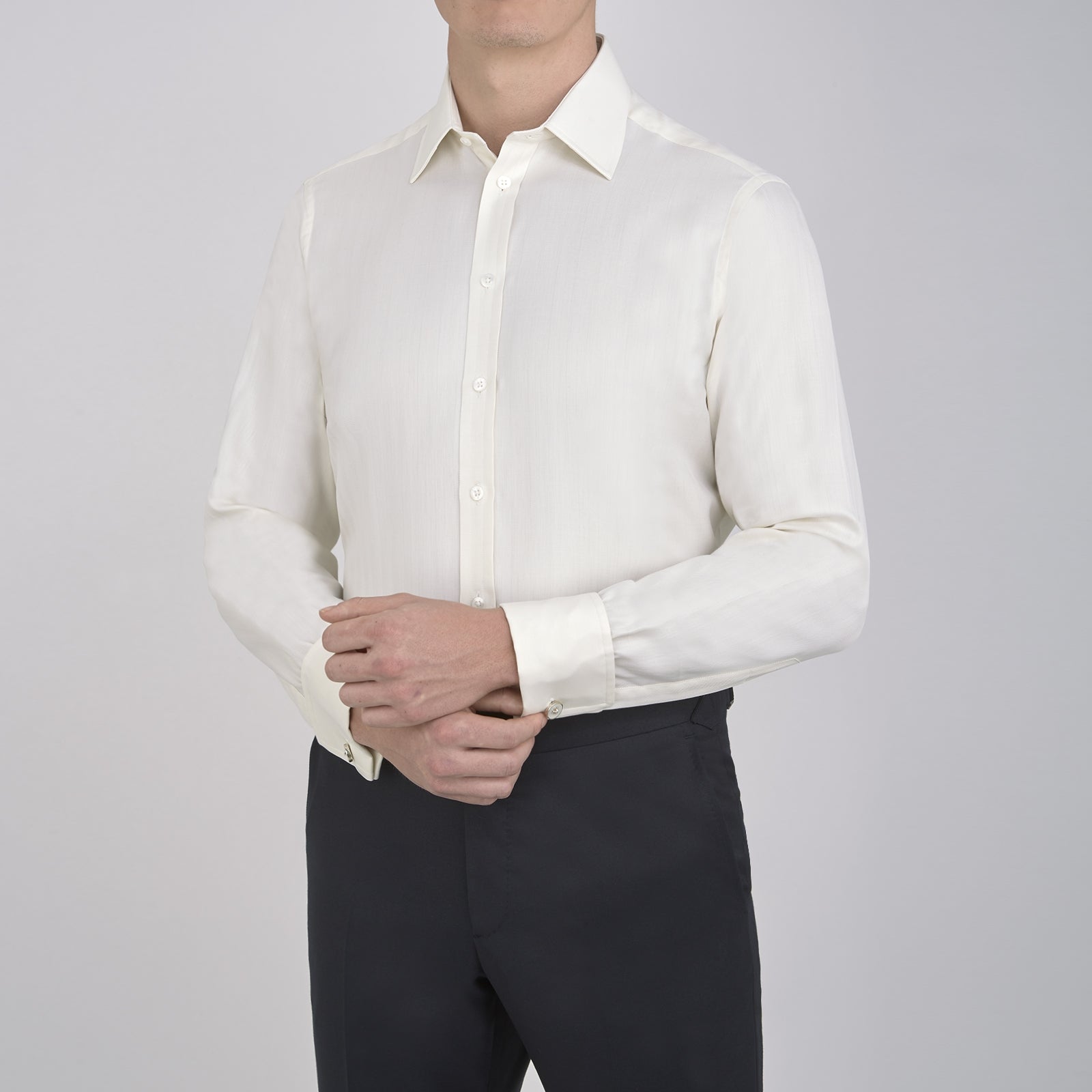 View 2 of product The Turnbull & Asser Cream Herringbone Superfine Cotton Shirt features a T&A collar, double cuffs, and a subtle pattern. It is neatly folded with white buttons and displayed on a plain white background.