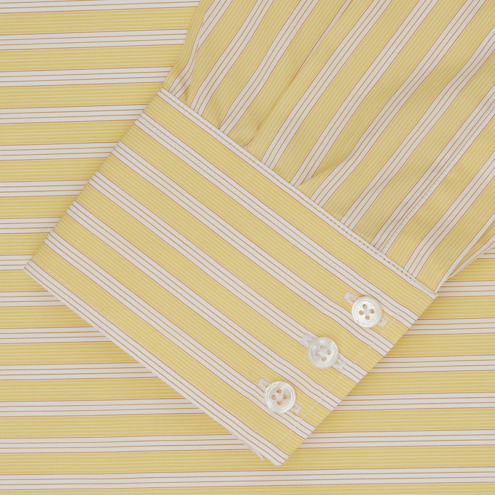 The Turnbull & Asser Yellow and White Bold Stripe Shirt features a T&A collar, 3-button cuffs, and white buttons. Displayed neatly folded on a plain white background, this long-sleeve shirt is perfect for office wear.
