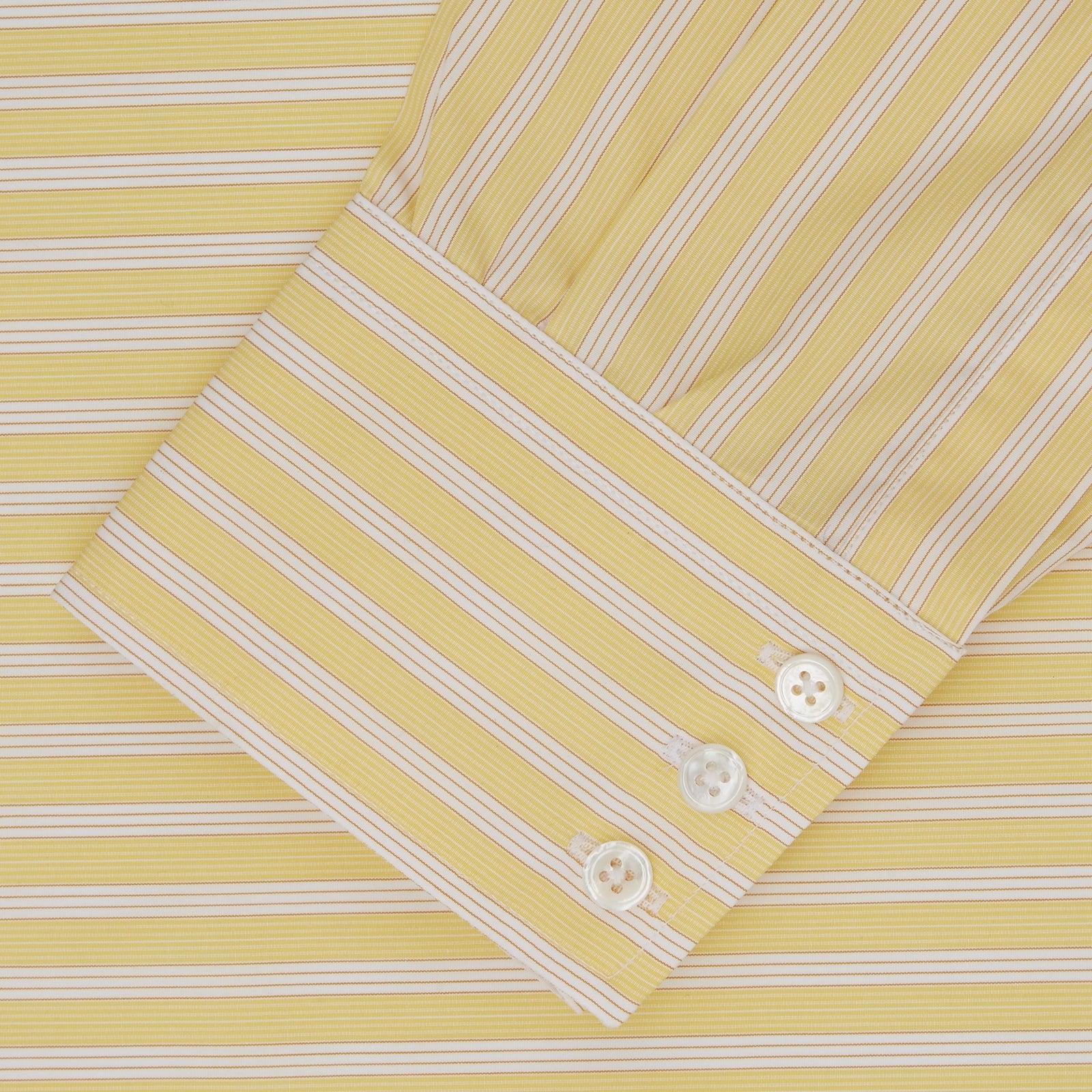 View 2 of product The Turnbull & Asser Yellow and White Bold Stripe Shirt features a T&A collar, 3-button cuffs, and white buttons. Displayed neatly folded on a plain white background, this long-sleeve shirt is perfect for office wear.