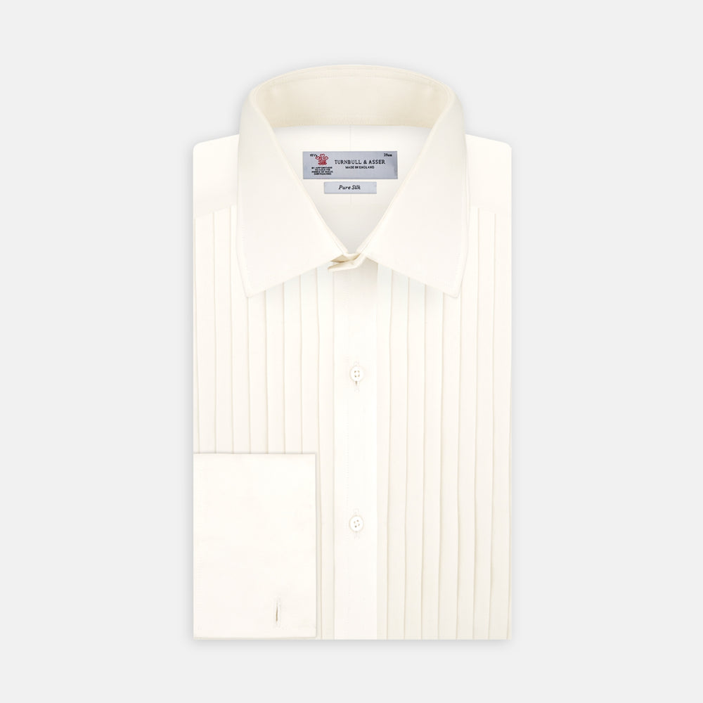 The Turnbull & Asser Tailored Fit Cream Pleated Front Silk Dress Shirt with T&A collar and double cuffs is displayed neatly folded against a light gray background.