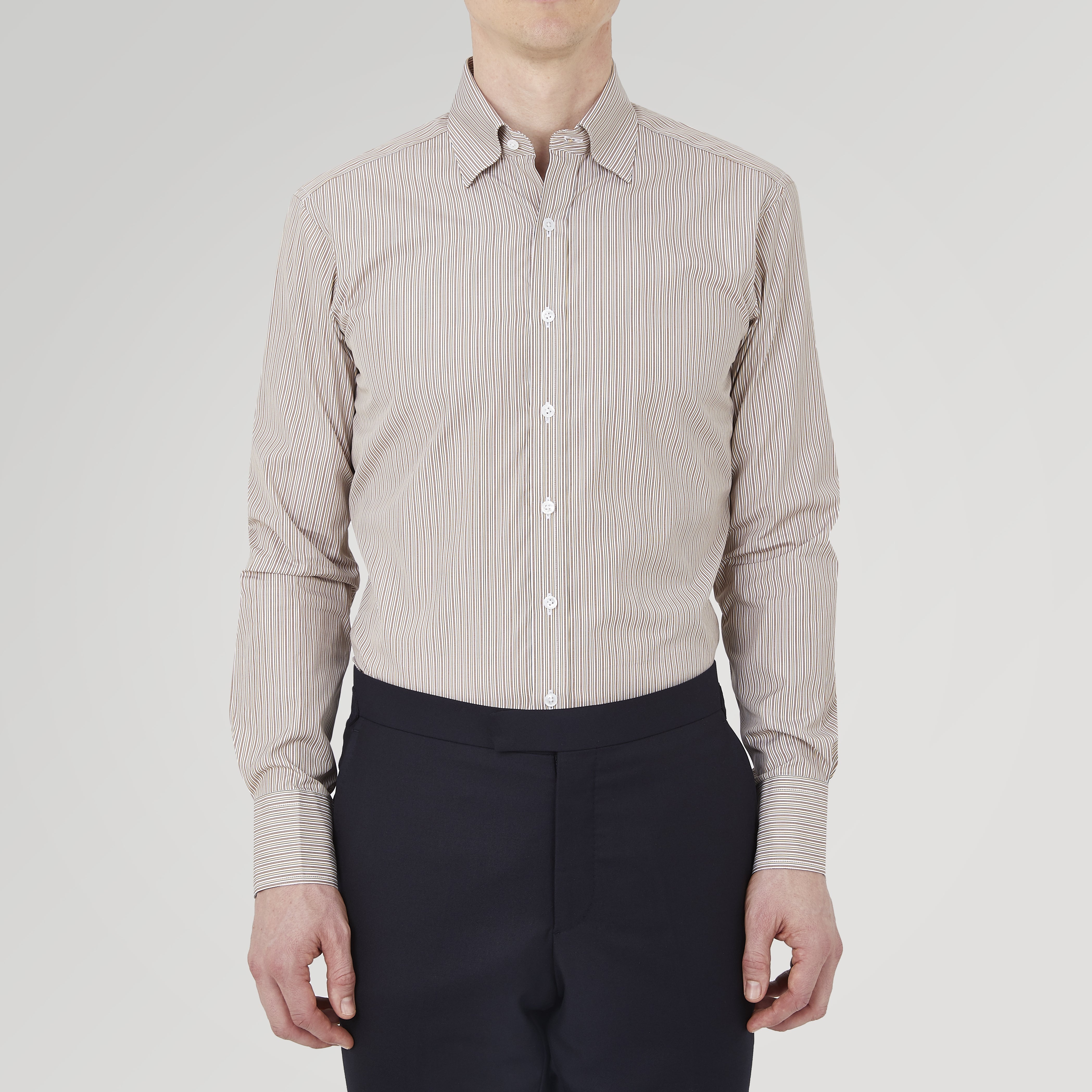 View 2 of product The Turnbull & Asser Tailored Fit Brown Fine Stripe Shirt features a Bury collar, 3-button cuffs, white buttons, and fine brown and white stripes. Made from premium Thomas Mason cotton and shown neatly folded on a plain white background.