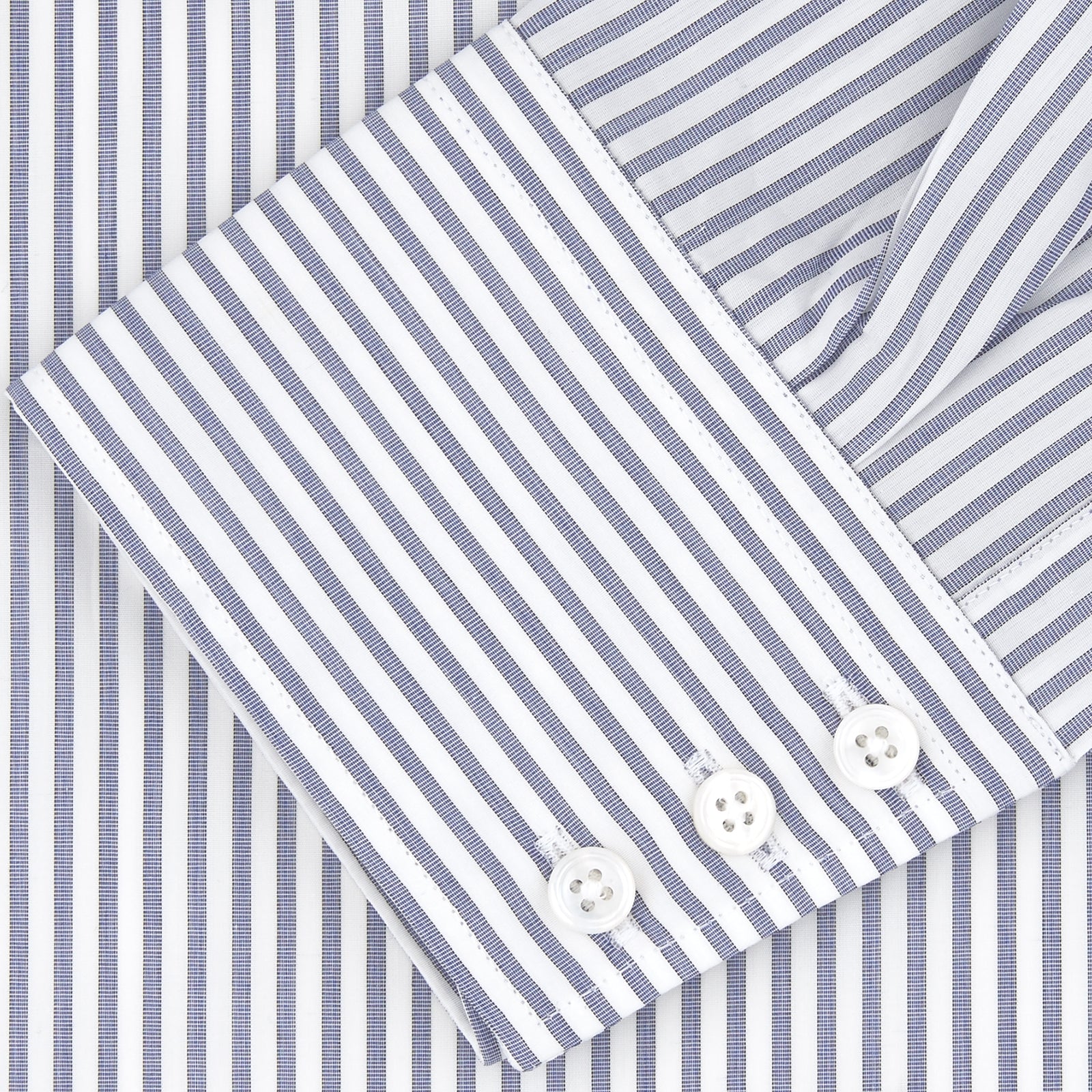 View 4 of product The Turnbull & Asser Tailored Fit Blue and White Stripe Sea Island Quality Cotton Shirt features a Bury collar and 3-button cuffs, neatly folded with white buttons, shown on a plain white background.