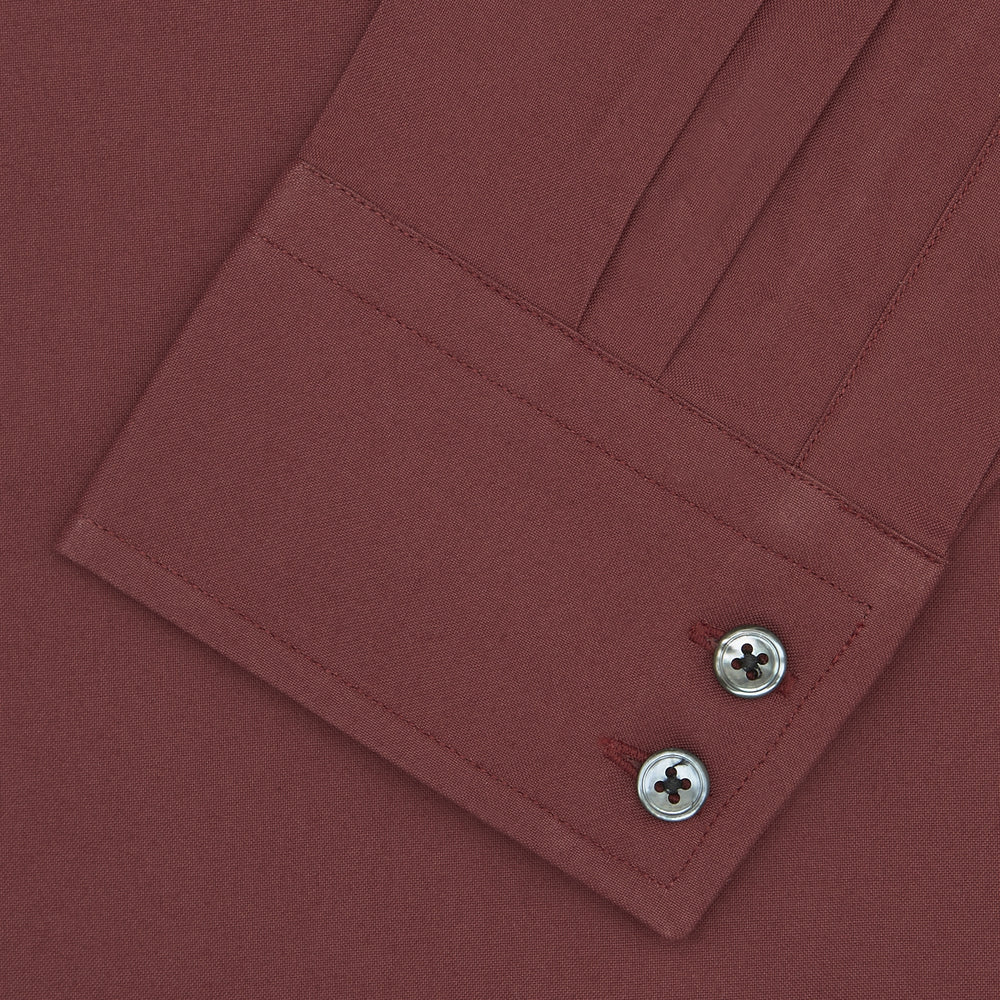 The Turnbull & Asser Tailored Fit Burgundy Cotton Shirt features a classic Kent collar and 2-button cuffs, displayed neatly folded with dark buttons against a plain white background.