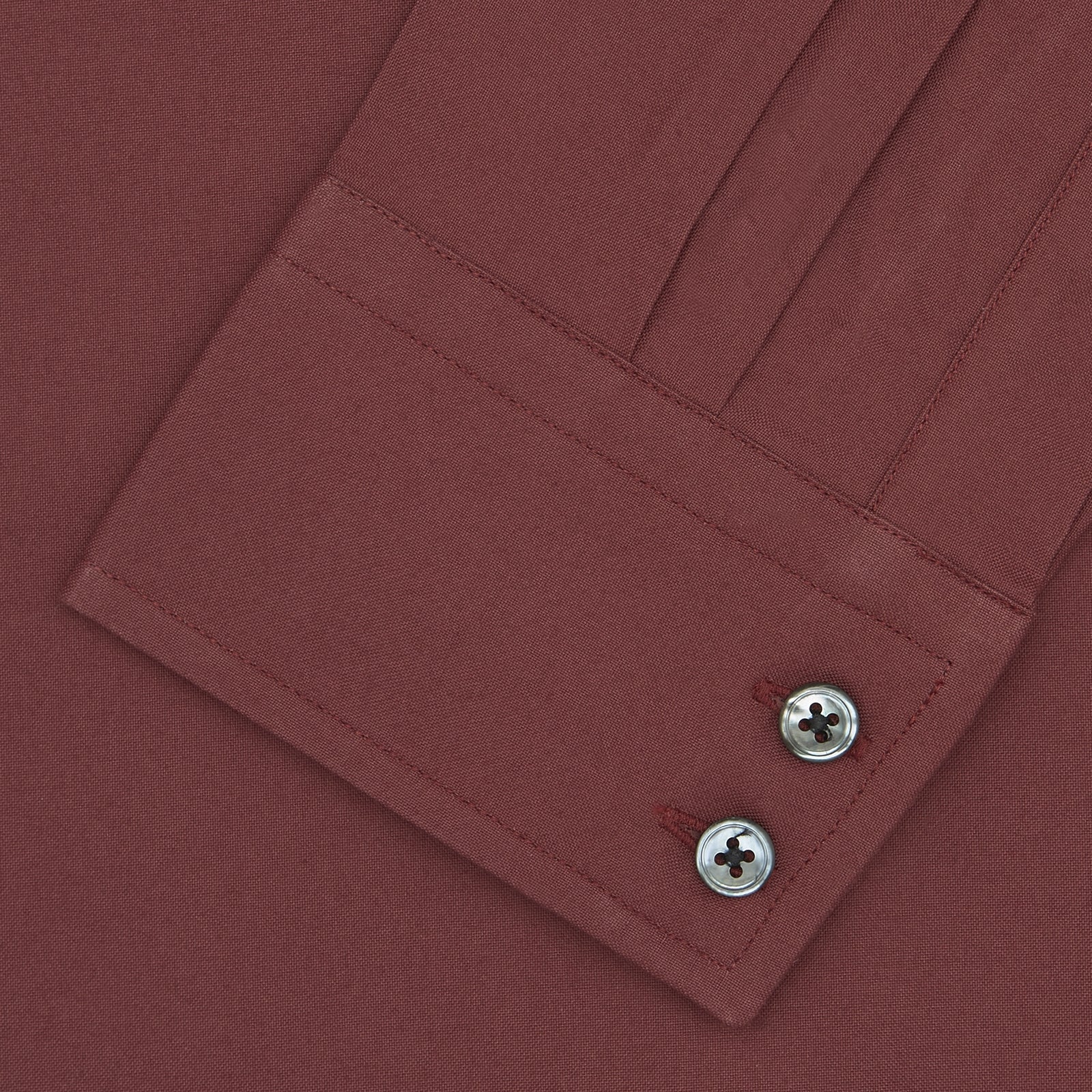 View 2 of product The Turnbull & Asser Tailored Fit Burgundy Cotton Shirt features a classic Kent collar and 2-button cuffs, displayed neatly folded with dark buttons against a plain white background.