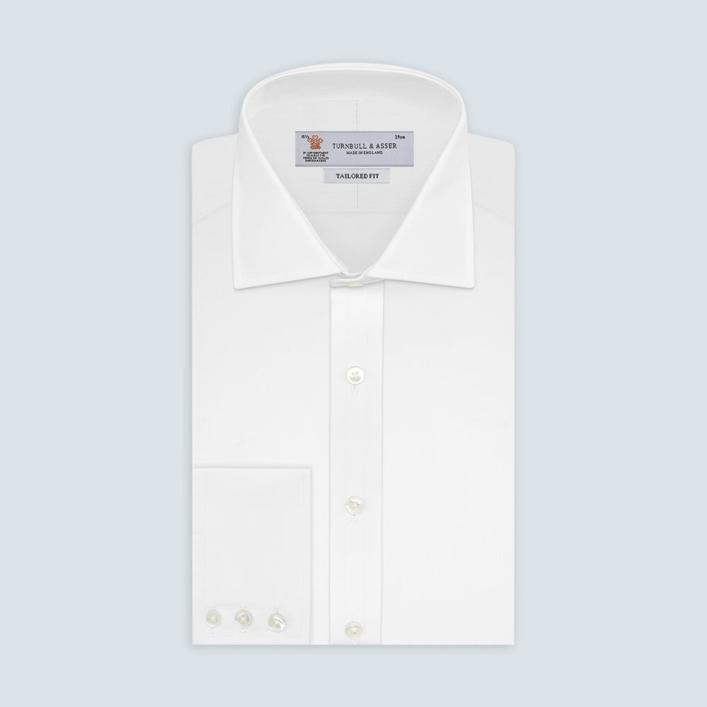 A neatly folded white Turnbull & Asser shirt, tailored fit with a Kent collar and 3BC PLA details, pearl-like buttons, and signature cuffs, is displayed against a light grey background. The label reads Turnbull & Asser.