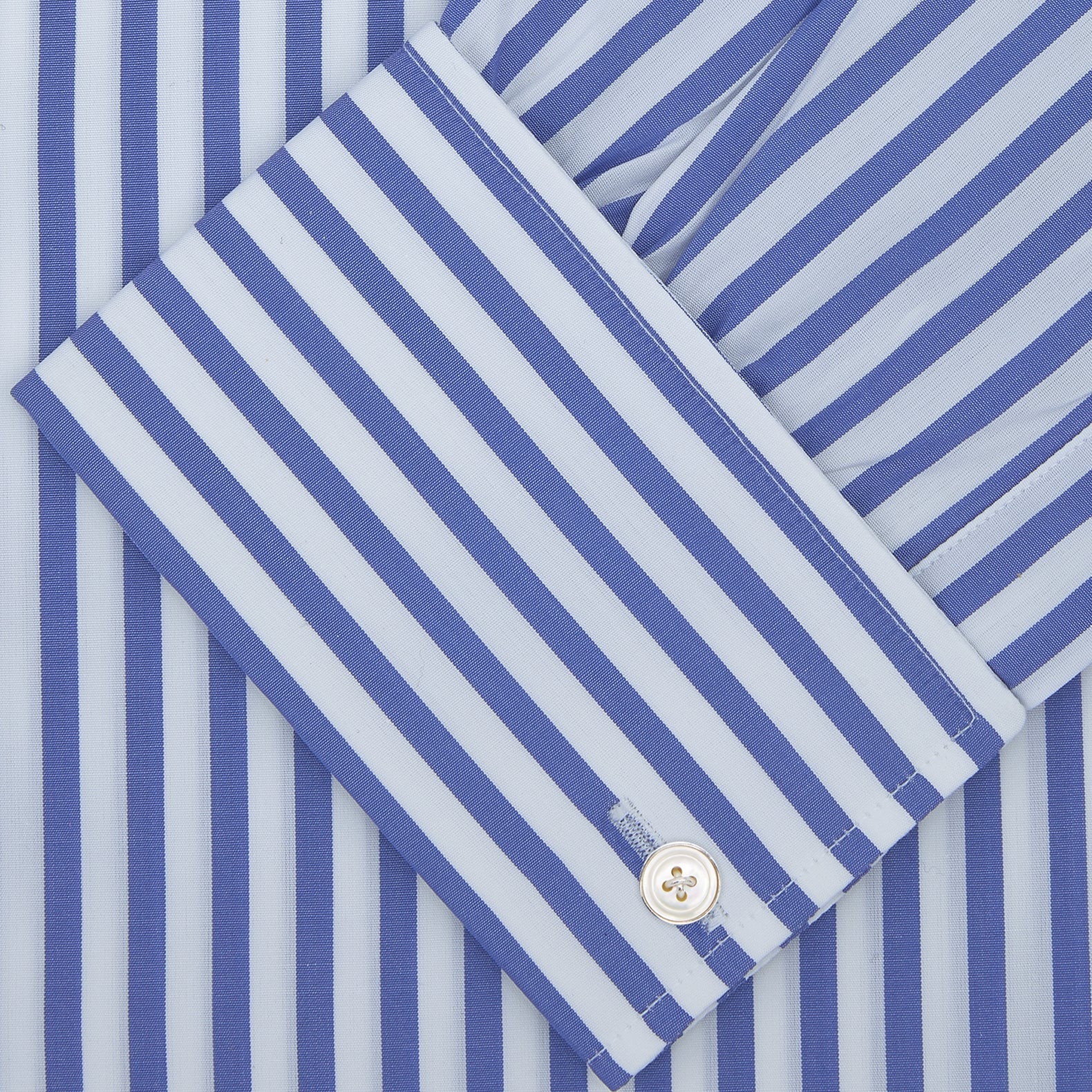 View 2 of product The Turnbull & Asser Blue and White Candy Stripe Shirt features a Regent collar, double cuffs, and white buttons, neatly folded against a plain white background.
