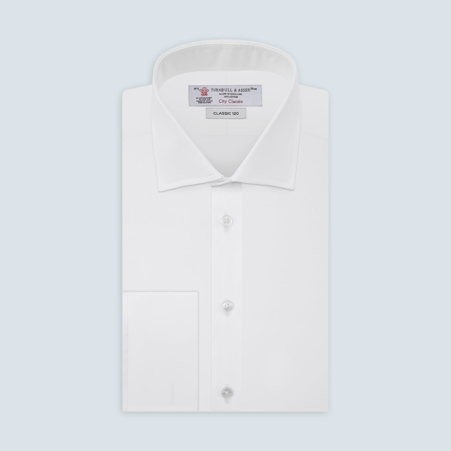 View 1 of product The Turnbull & Asser Two-Fold 120 White Cotton Shirt features long sleeves, a regent collar, double cuffs, and white buttons, neatly displayed against a light blue background.