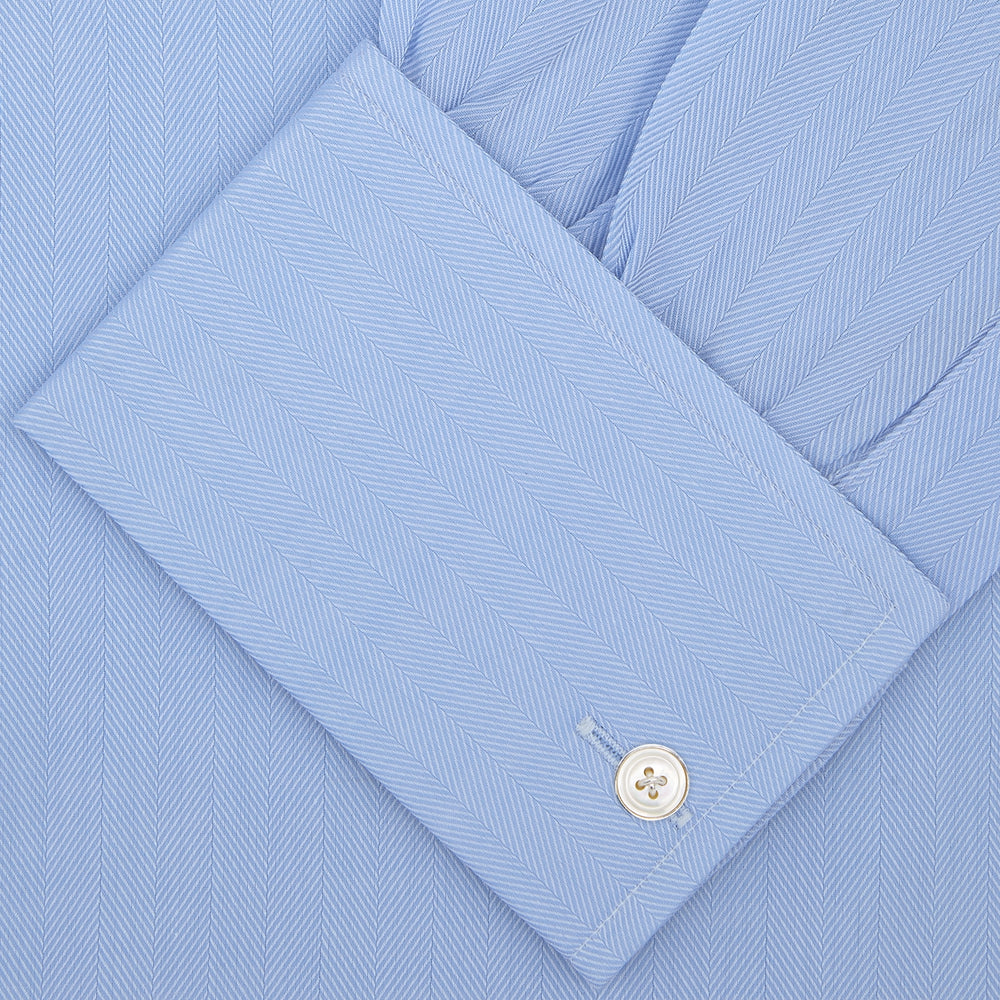 The Turnbull & Asser Light Blue Herringbone Superfine Cotton Shirt features a T&A collar, double cuffs, and is neatly folded against a plain white background.