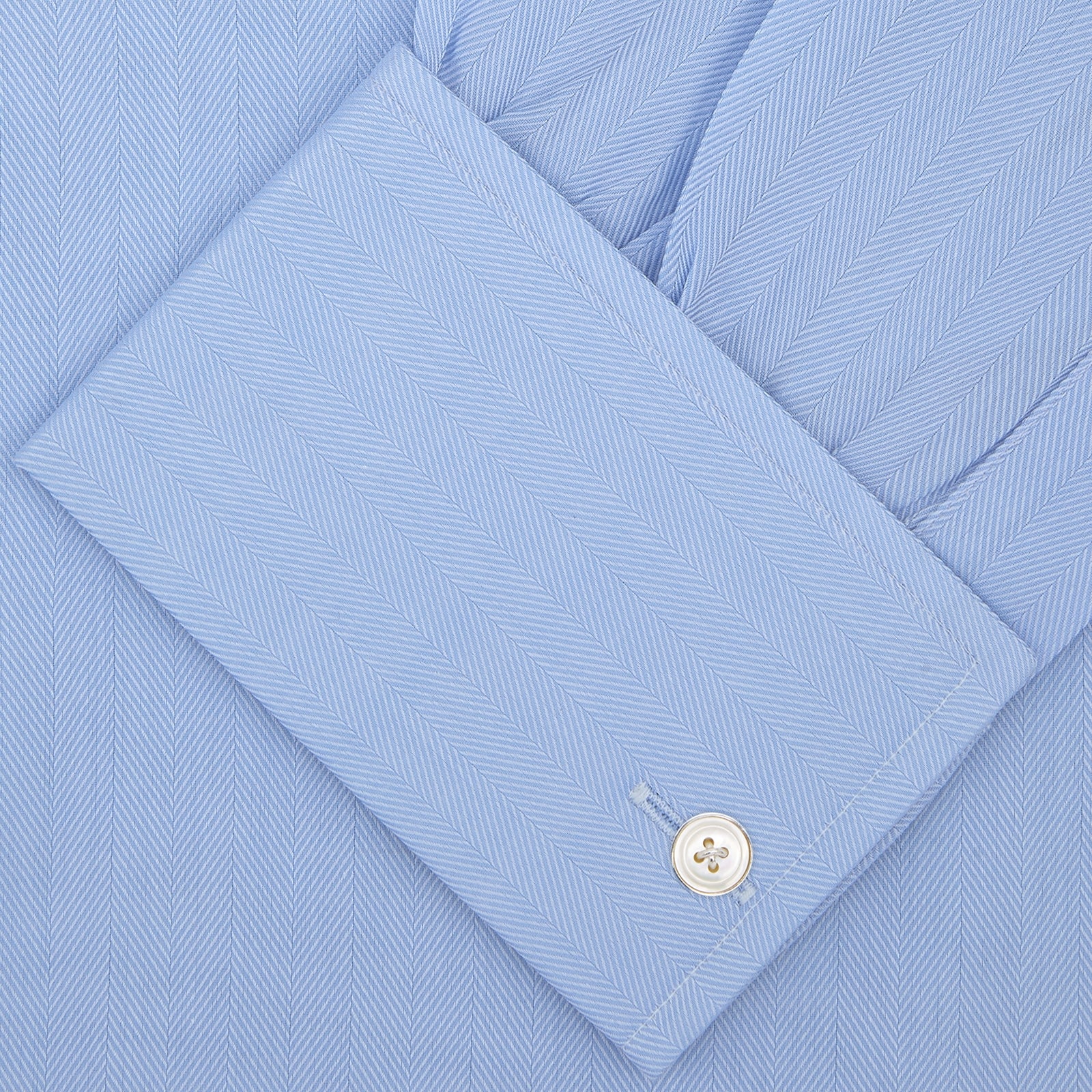 View 2 of product The Turnbull & Asser Light Blue Herringbone Superfine Cotton Shirt features a T&A collar, double cuffs, and is neatly folded against a plain white background.