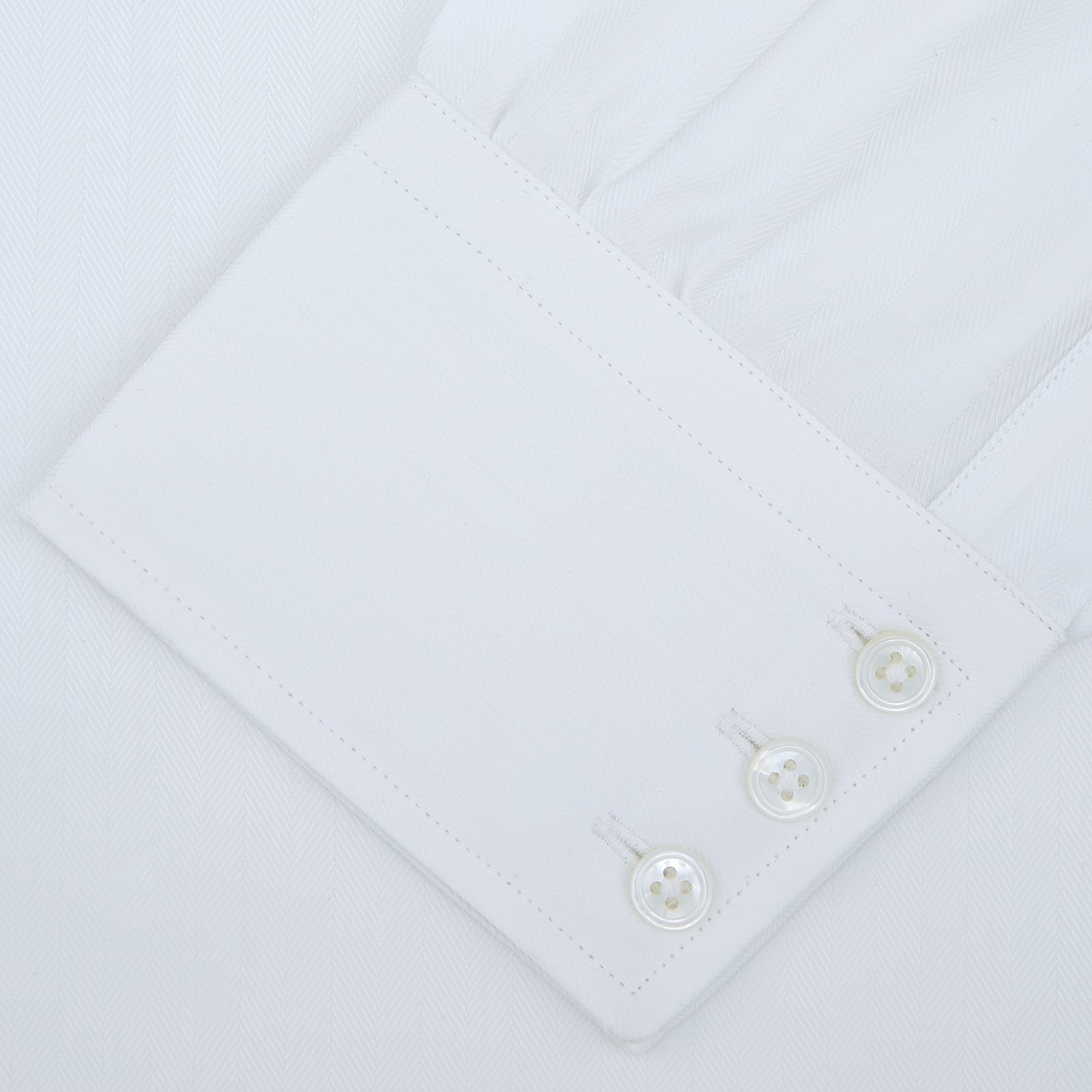View 2 of product A Turnbull & Asser White Self-On-Self Herringbone Sea Island Quality Cotton Shirt with a Regent collar and 3-button cuffs, neatly folded and displayed on a light grey background.