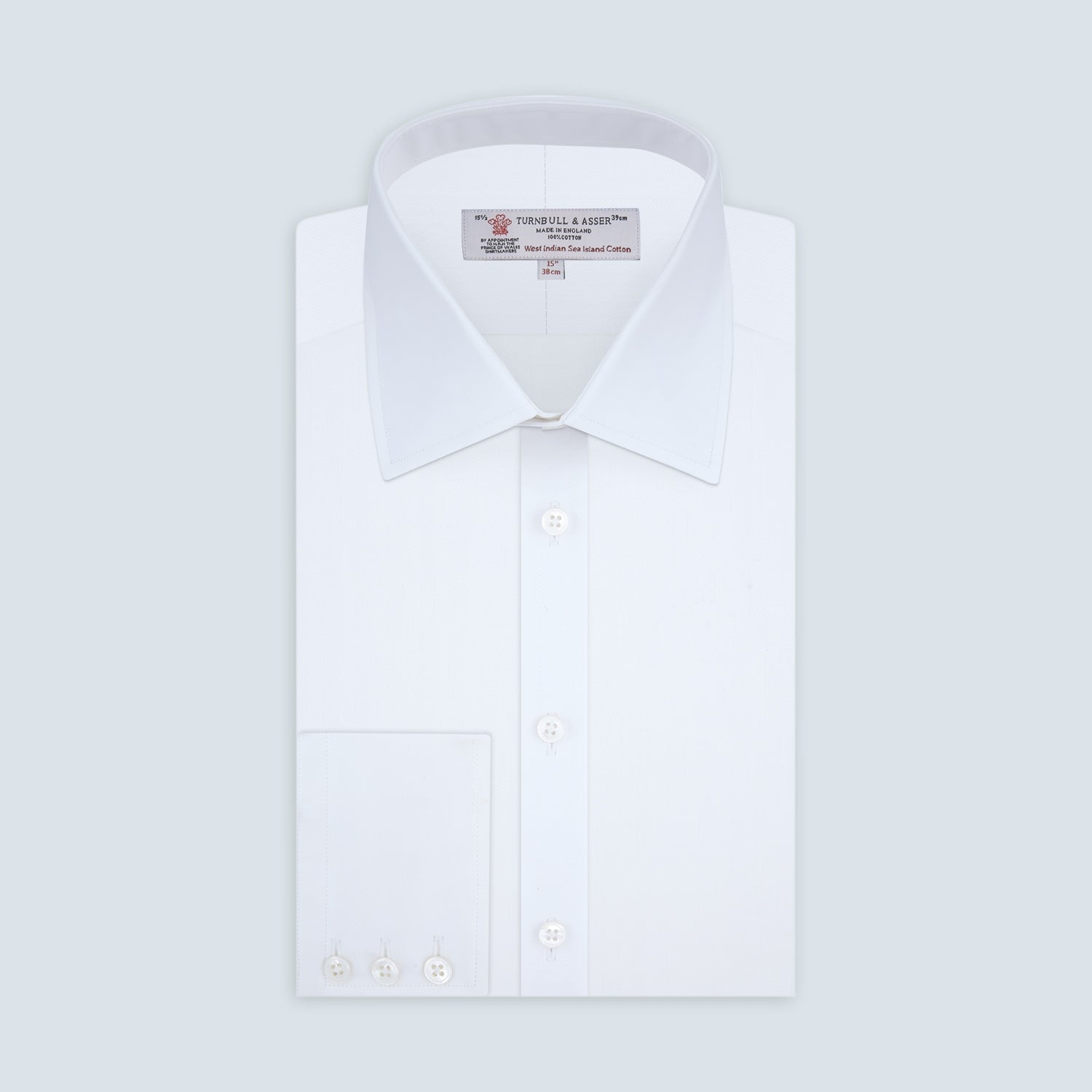 View 1 of product A Turnbull & Asser White Self-On-Self Herringbone Sea Island Quality Cotton Shirt with a Regent collar and 3-button cuffs, neatly folded and displayed on a light grey background.