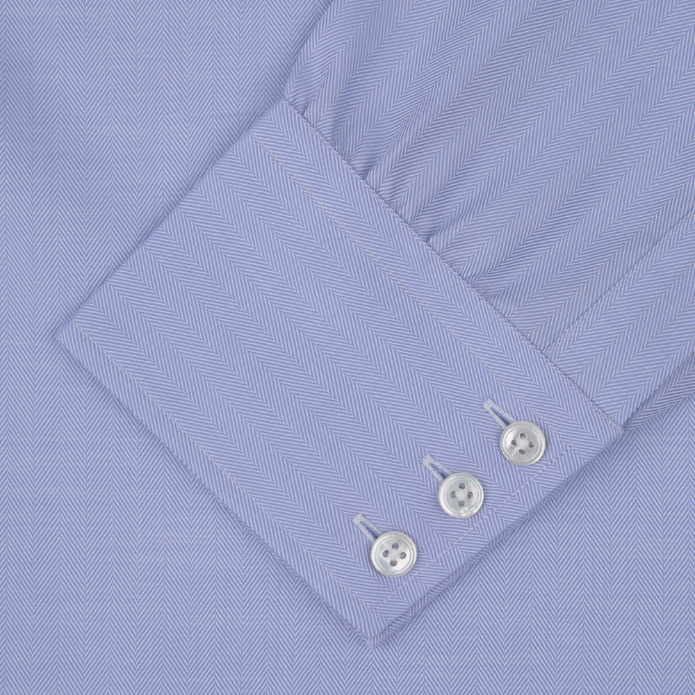The Blue Herringbone Sea Island Quality Cotton Shirt by Turnbull & Asser features a T&A collar, 3-button cuffs, and is crafted from luxurious cotton. The shirt is displayed neatly folded on a plain white background.