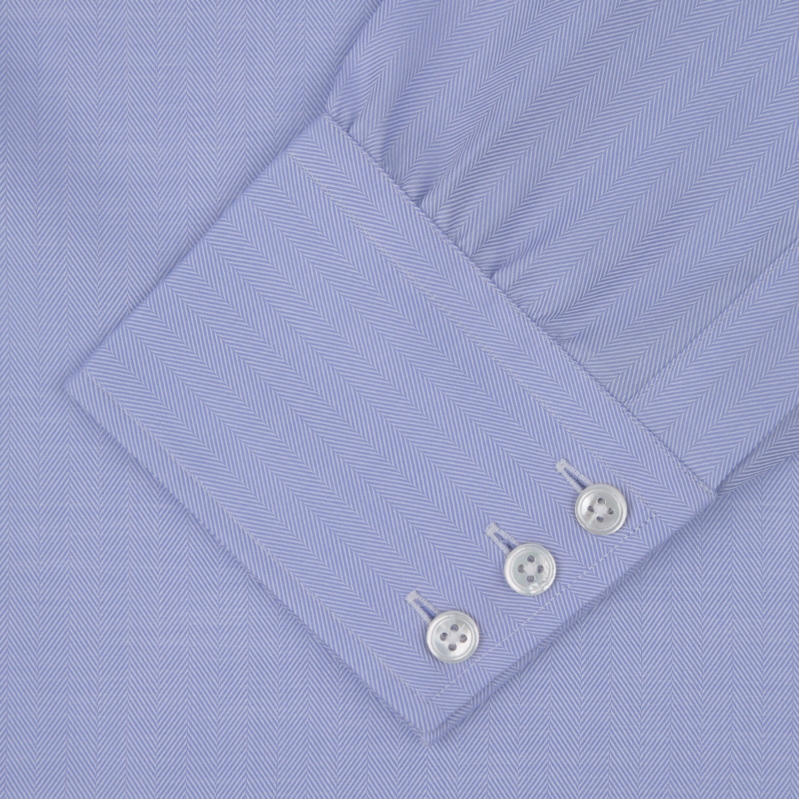 View 4 of product The Blue Herringbone Sea Island Quality Cotton Shirt by Turnbull & Asser features a T&A collar, 3-button cuffs, and is crafted from luxurious cotton. The shirt is displayed neatly folded on a plain white background.