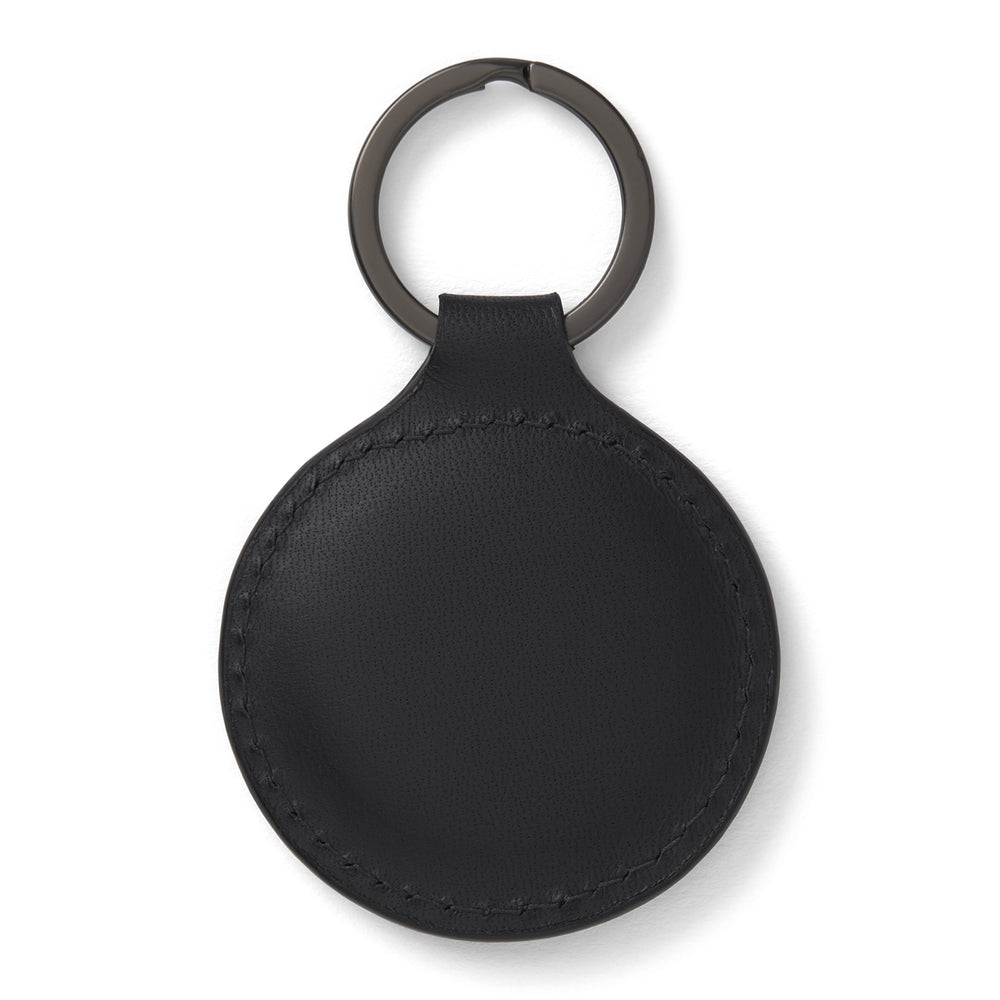 The Black Leather Key Fob from Turnbull & Asser features a round black leather design with a metal ring, embossed with the brand logo and "MADE IN ENGLAND"—an elegant key accessory for any collection.
