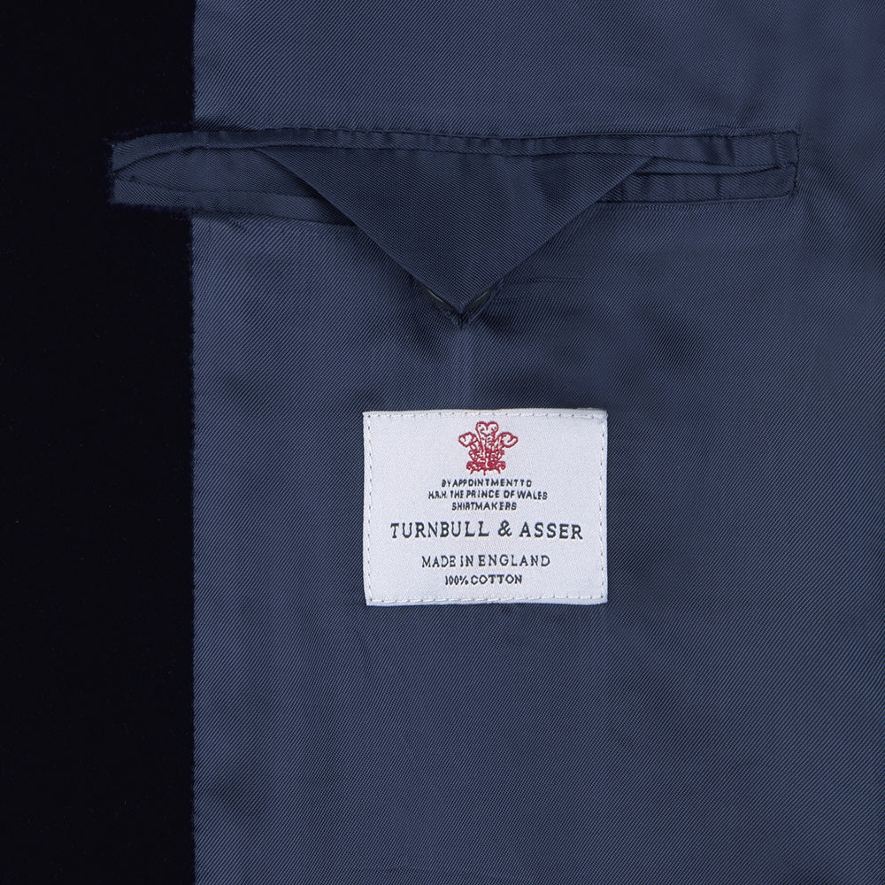 Turnbull & Asser's MSMJ004-ZCS002 "Fergus" velvet smoking jacket in navy features a shawl collar, single decorative knot closure, and two front pockets, shown against a white background.