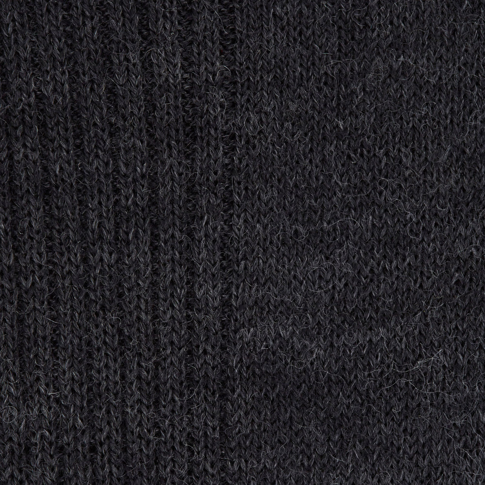 A single Charcoal Mid-Length Merino Wool Sock by Turnbull & Asser stands upright on a light gray background, its dark ribbed fabric and angled foot showcased.