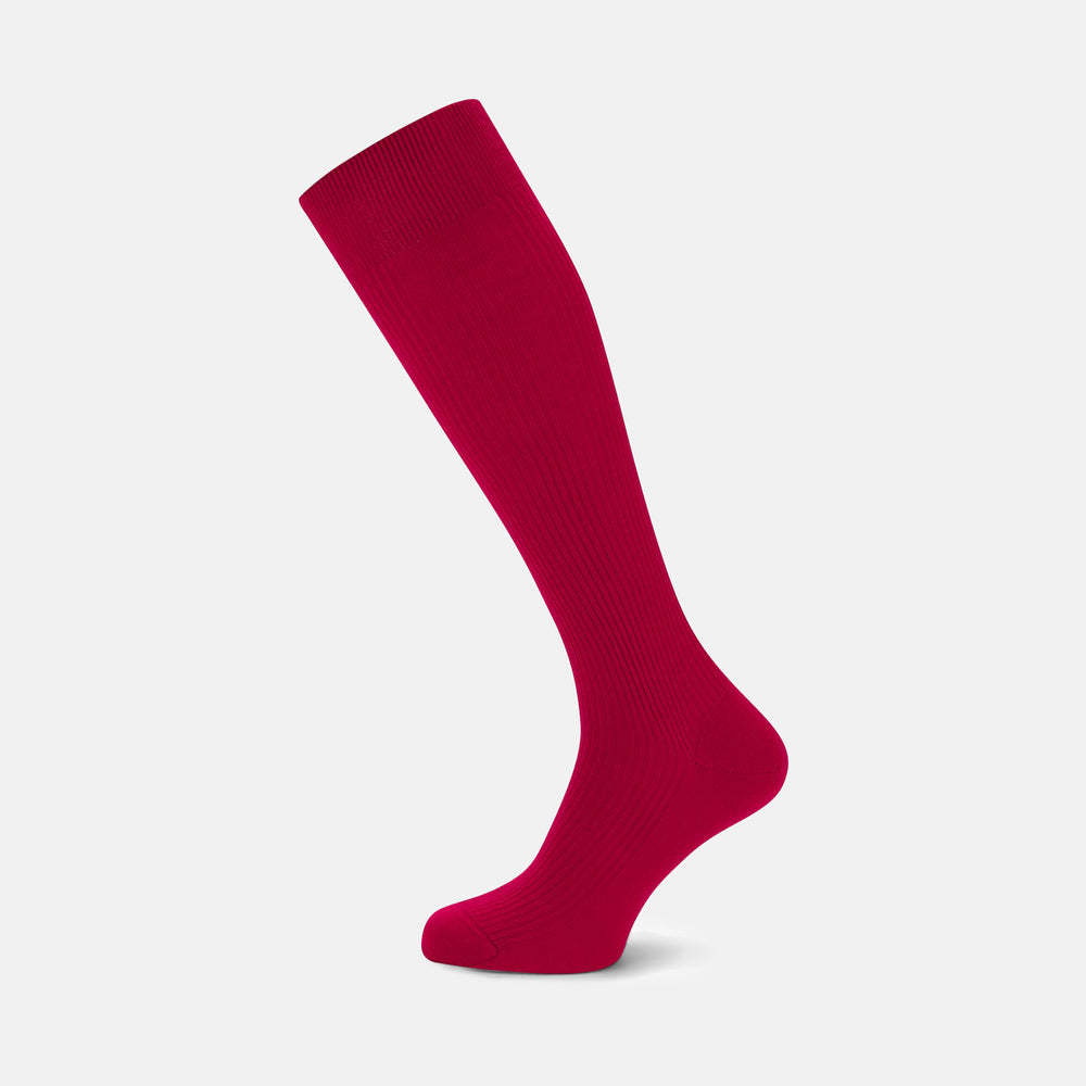 A single Red Long Merino Wool Sock by Turnbull & Asser stands upright against a light gray background, highlighting the elegance and luxury of premium men’s socks.