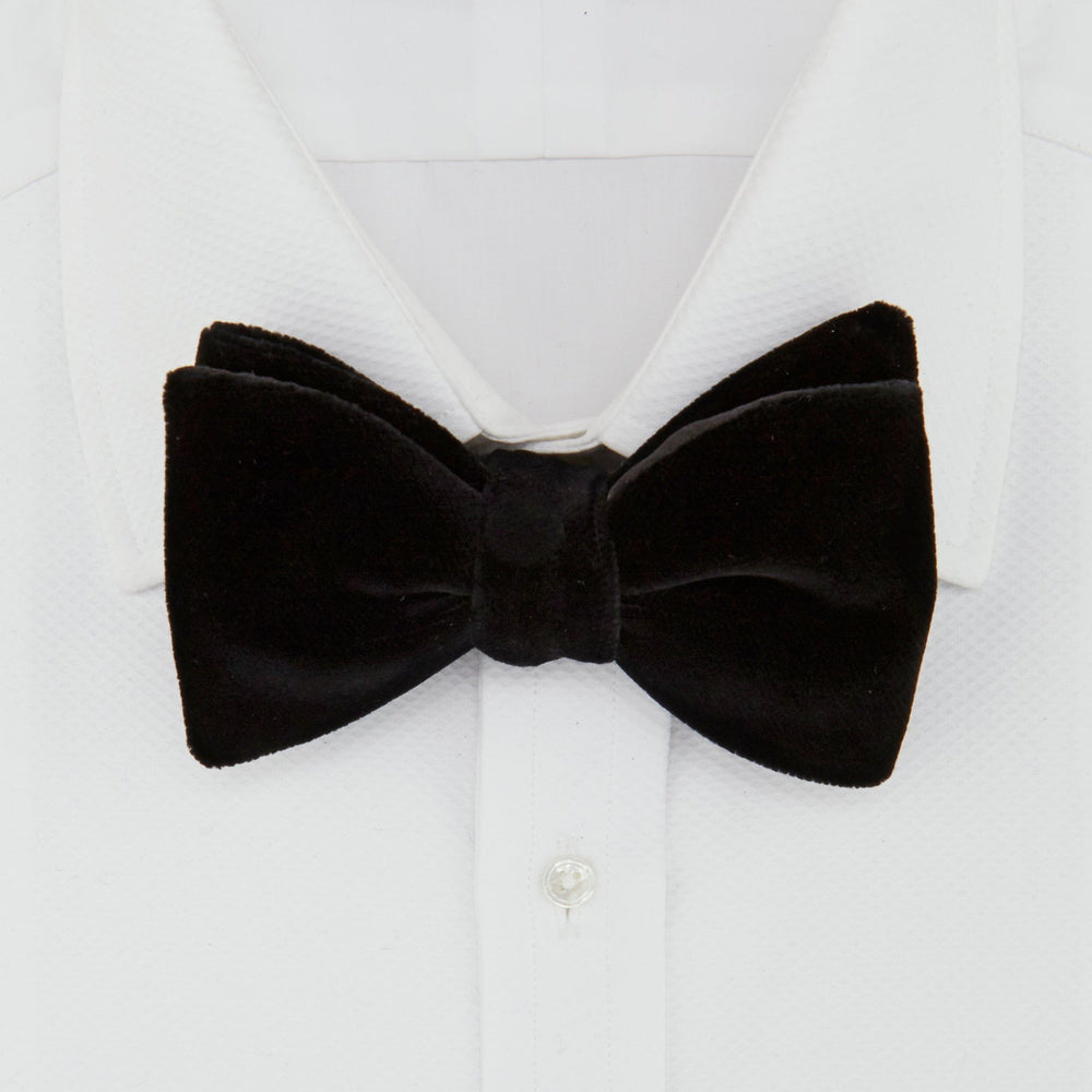 The Turnbull & Asser Black Velvet Bow Tie, shown against a plain white background, is an elegant choice for formal occasions.