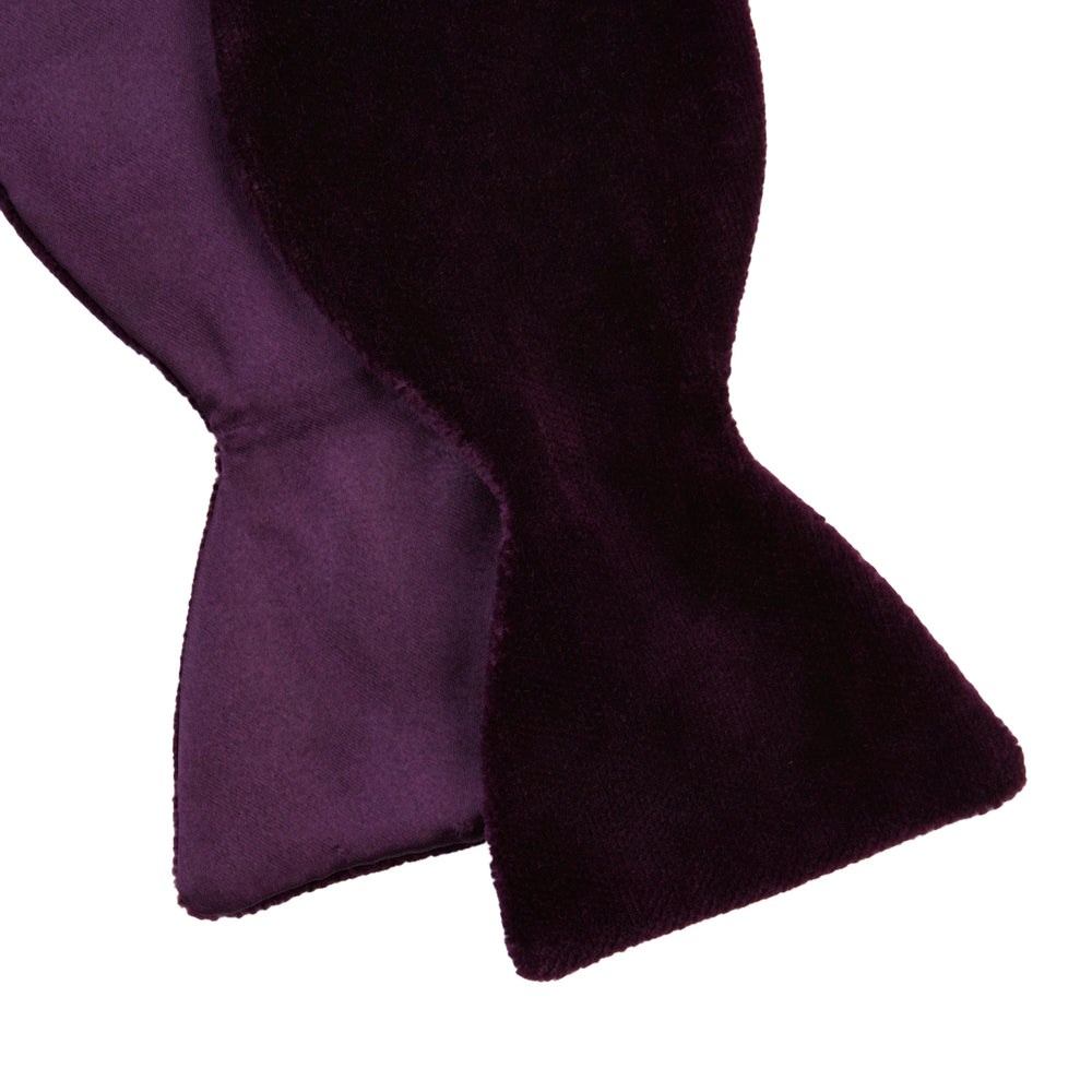The Turnbull & Asser Purple Velvet Bow Tie is showcased on a plain white background, offering an elegant accessory to elevate any formal outfit with sophistication.