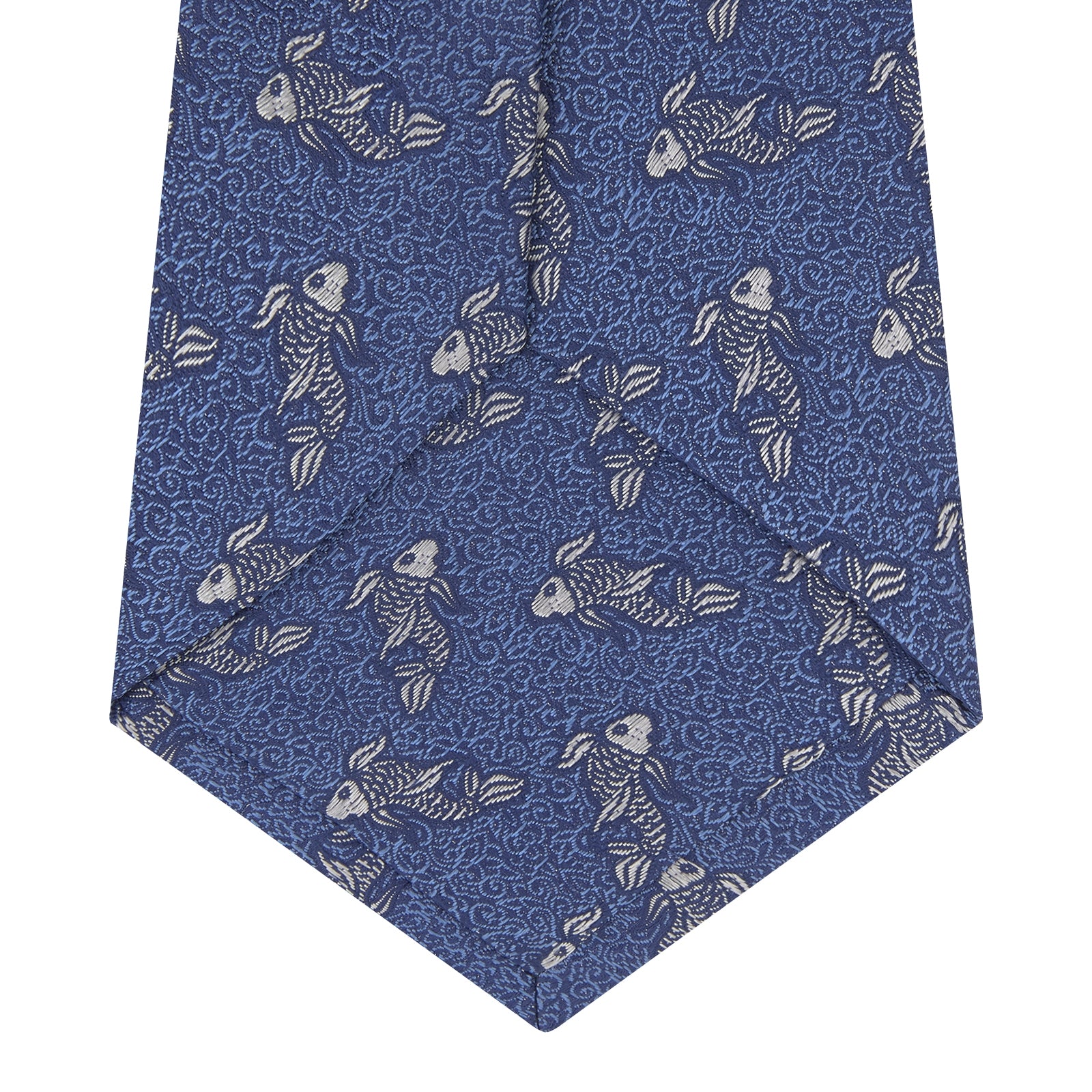 View 4 of product The Blue Carp Silk Tie by Turnbull & Asser features a blue silk base with white and dark blue koi fish among light blue swirls. The tie is displayed rolled up, pointed end forward.