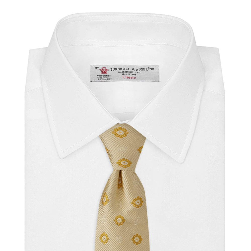 The Turnbull & Asser Soft Yellow Floral Jacquard Stripe Silk Tie features a rolled-up beige design with subtle texture and small yellow floral patterns evenly spaced throughout.