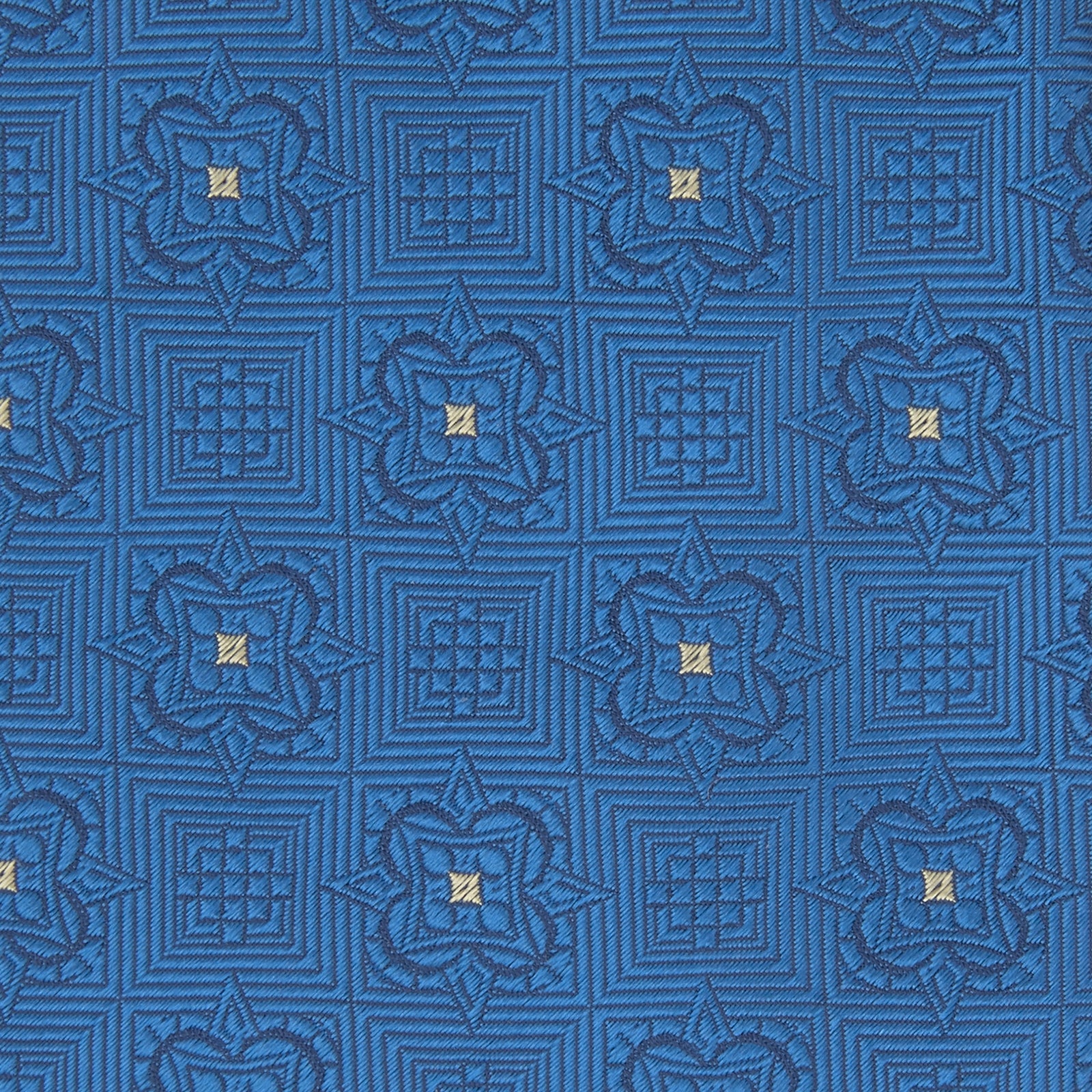View 3 of product The Turnbull & Asser Blue Flower Mosaic Silk Tie features a blue silk fabric with a detailed geometric and floral design, accented in lighter blue and white, displayed on a white background.