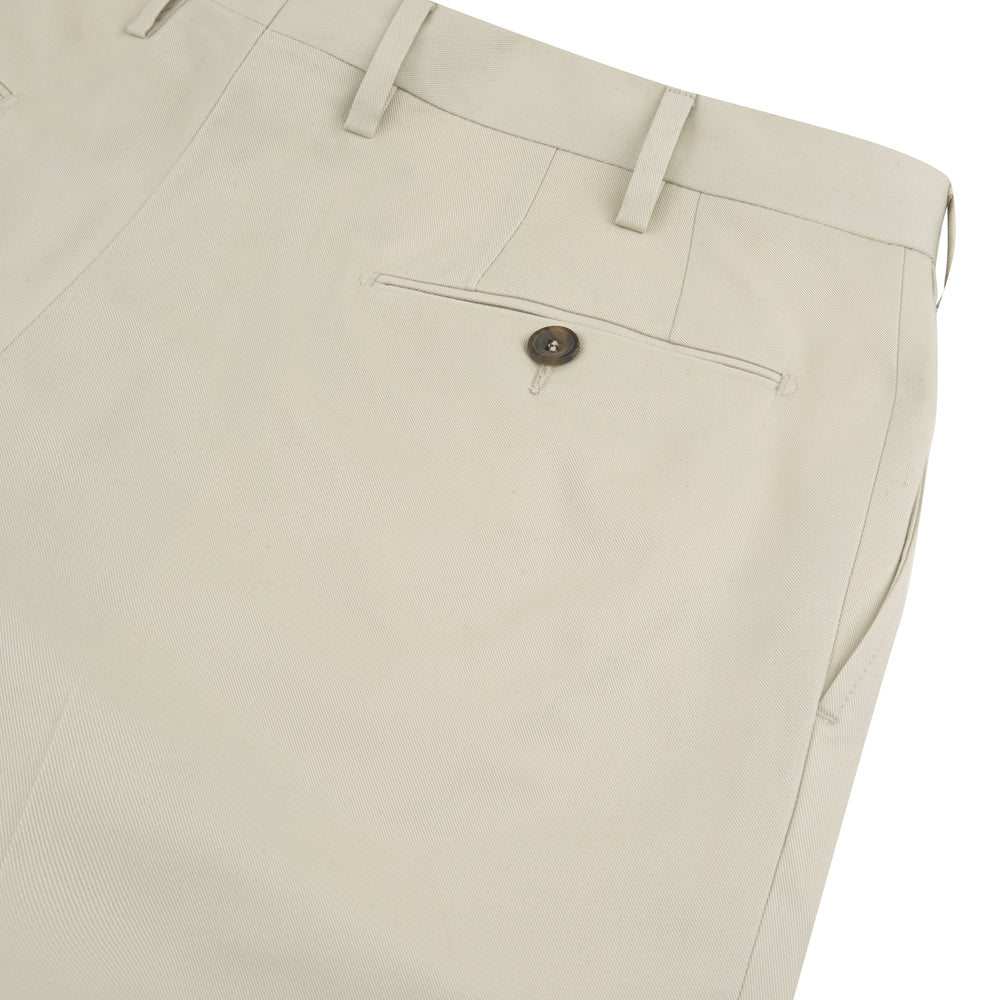 Turnbull & Asser's Stone Cotton Twill Pleated Trousers feature a relaxed fit, front pleats, side pockets, belt loops, and button closure, shown laid flat on a white background.