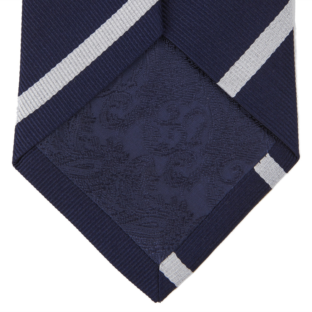 The Turnbull & Asser Seven-Fold Navy and White Blazer Stripe Repp Silk Tie, elegantly rolled at one end, is displayed on a plain white background.
