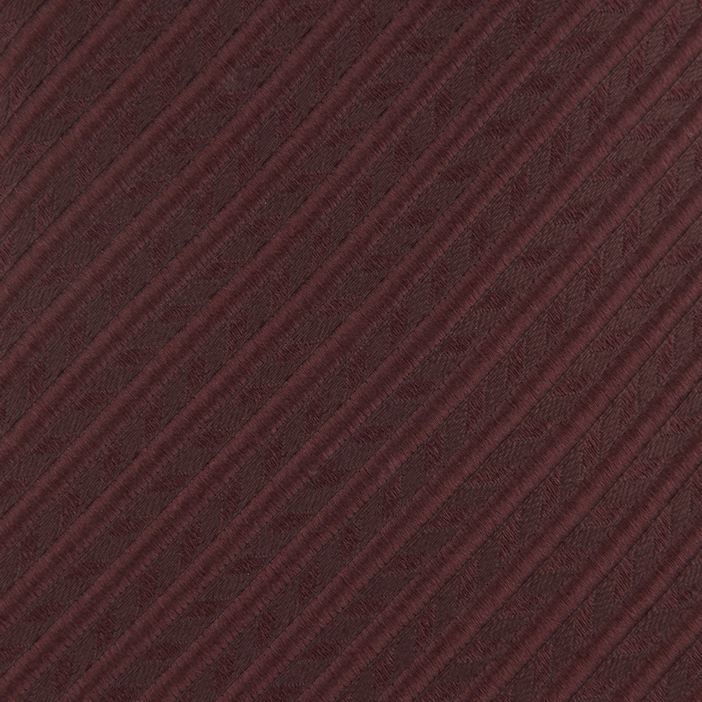 The Turnbull & Asser Burgundy Ottoman Silk Tie features a heavyweight ribbed silk with a subtle diagonal wave pattern, shown rolled up on a plain white background.