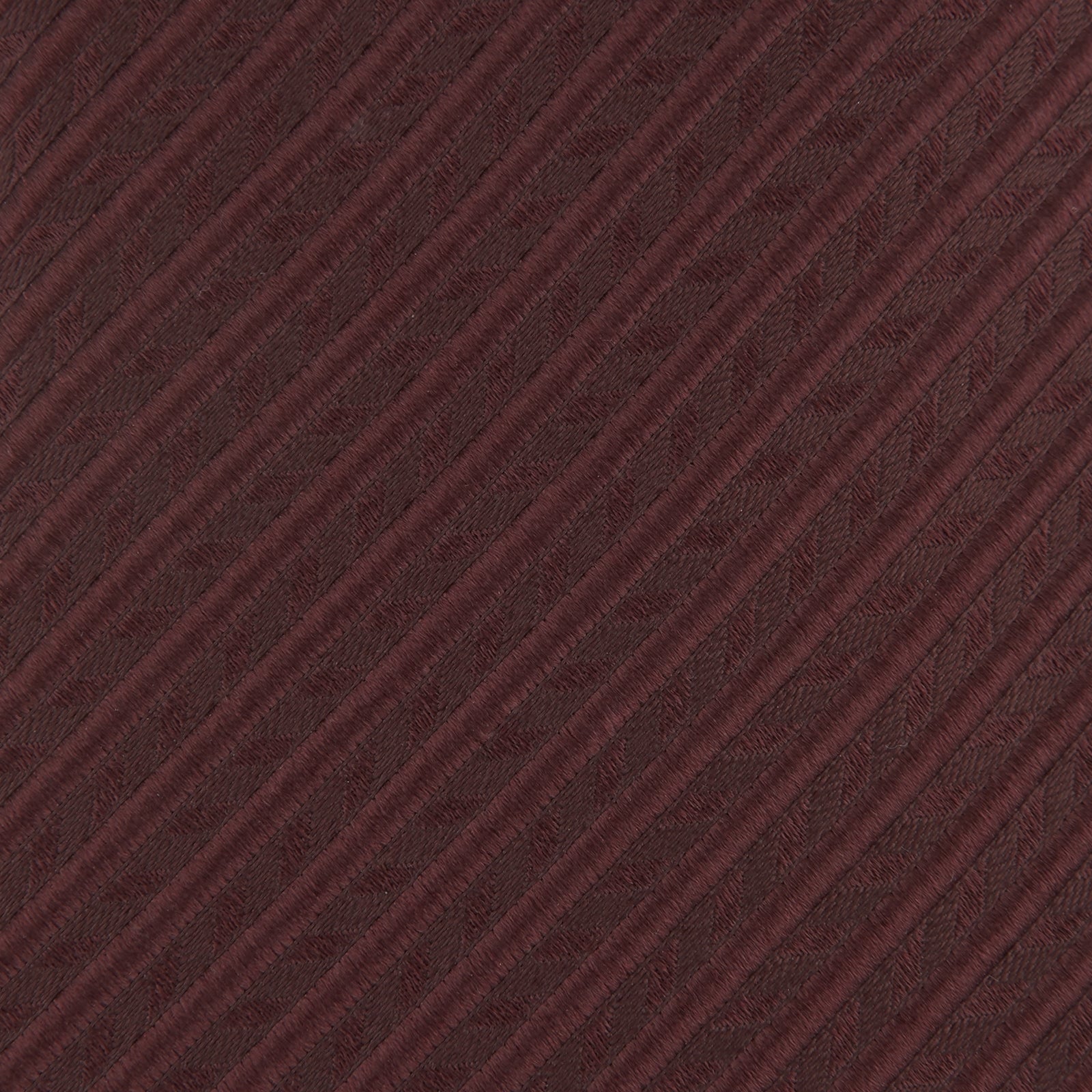 View 3 of product The Turnbull & Asser Burgundy Ottoman Silk Tie features a heavyweight ribbed silk with a subtle diagonal wave pattern, shown rolled up on a plain white background.