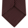 View 4 of product The Turnbull & Asser Burgundy Ottoman Silk Tie features a heavyweight ribbed silk with a subtle diagonal wave pattern, shown rolled up on a plain white background.