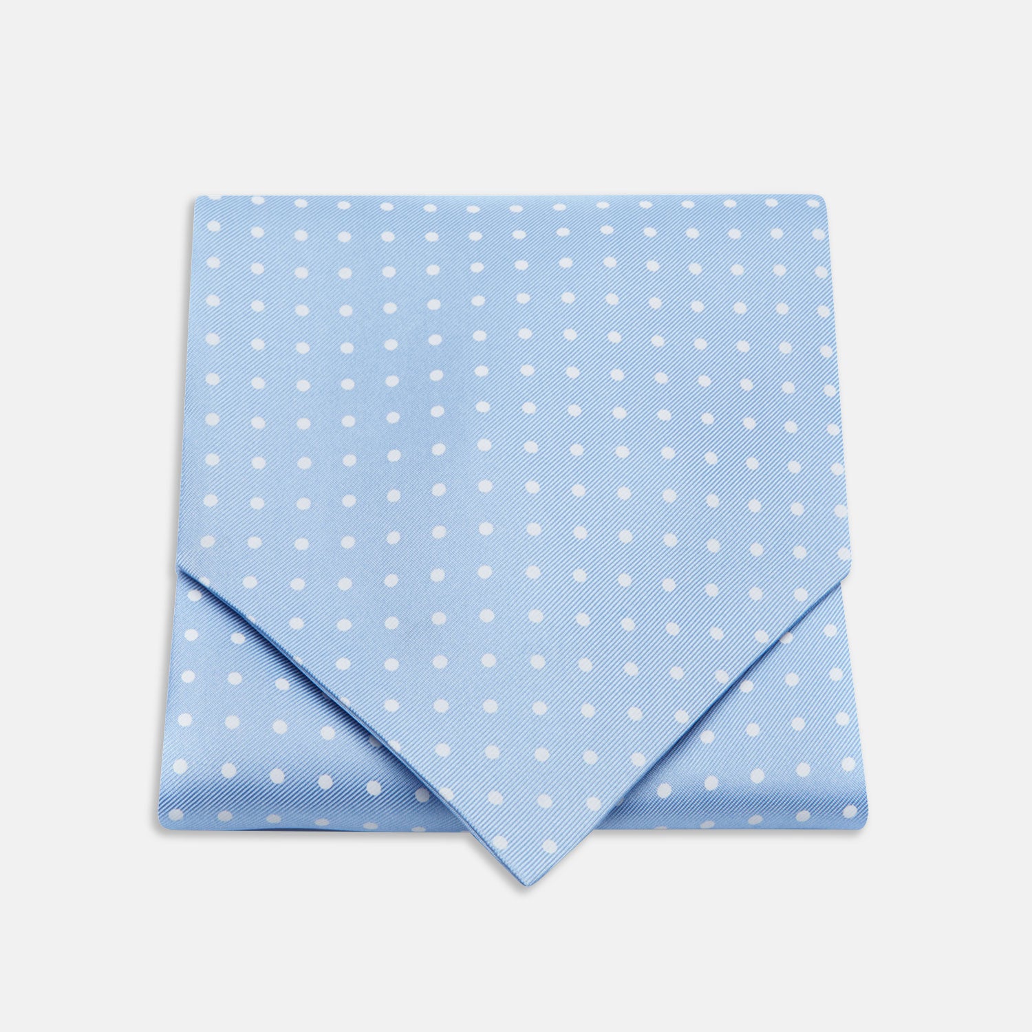 View 1 of product The Turnbull & Asser Sky Blue and White Medium Spot Silk Ascot Tie, neatly folded against a white background, is stylish neckwear—perfect for any wedding guest.