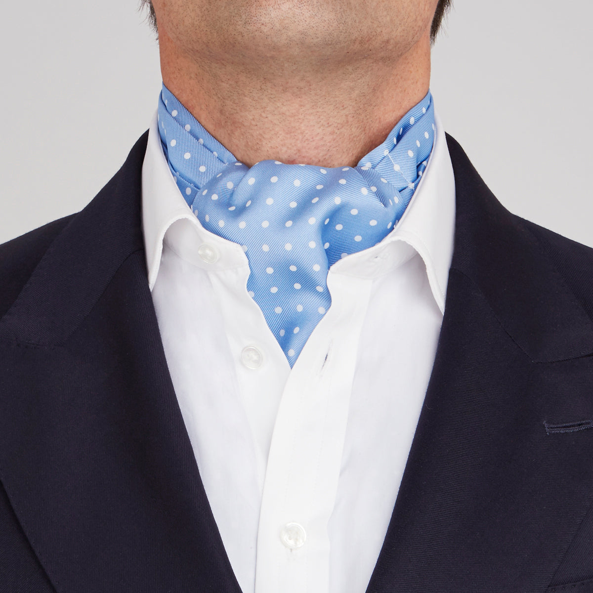 View 2 of product The Turnbull & Asser Sky Blue and White Medium Spot Silk Ascot Tie, neatly folded against a white background, is stylish neckwear—perfect for any wedding guest.