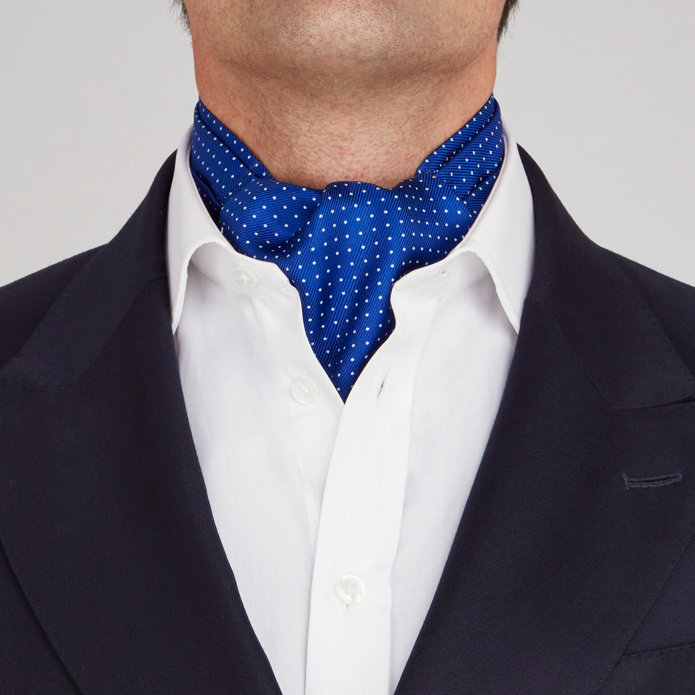 The Turnbull & Asser Royal Blue and White Small Spot Silk Ascot Tie, featuring fine white dots on blue silk, is shown on a plain white background—an elegant finishing touch for any wedding guest outfit.