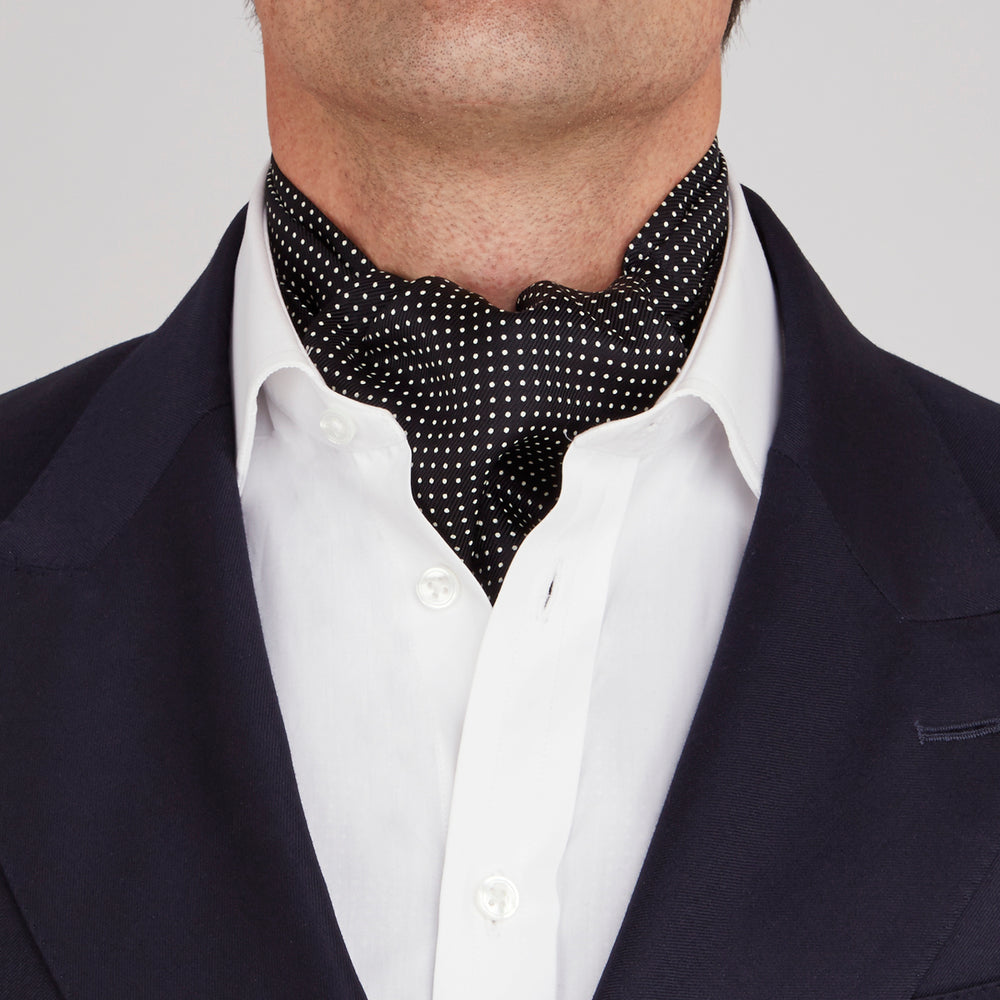 The Turnbull & Asser Black and White Mini Spot Silk Cravat, featuring a refined polka dot pattern, is displayed elegantly on a plain light background—an ideal wedding guest accessory.